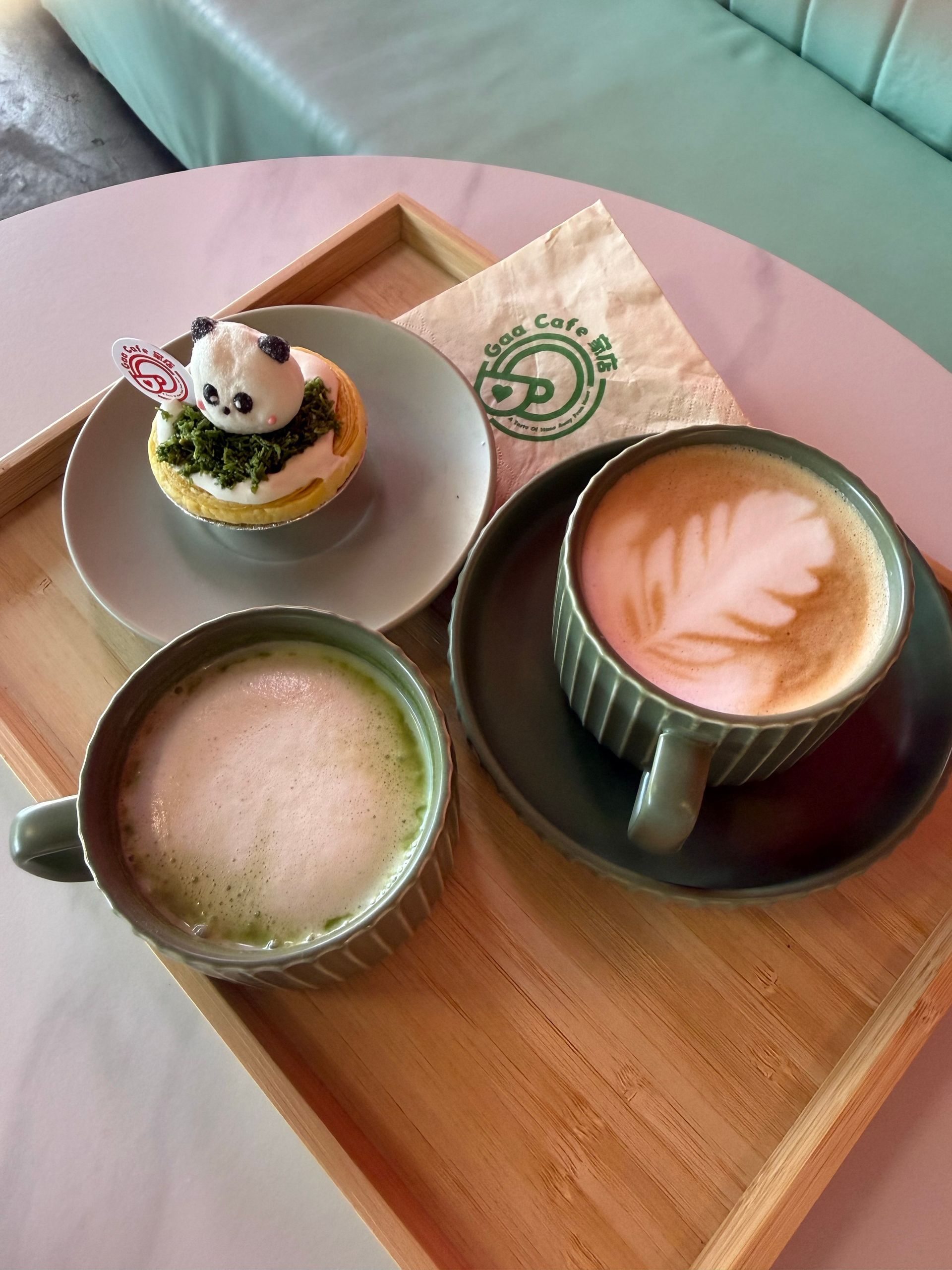 Coffee and dessert on a wooden tray: two lattes and a small pastry with a panda topper