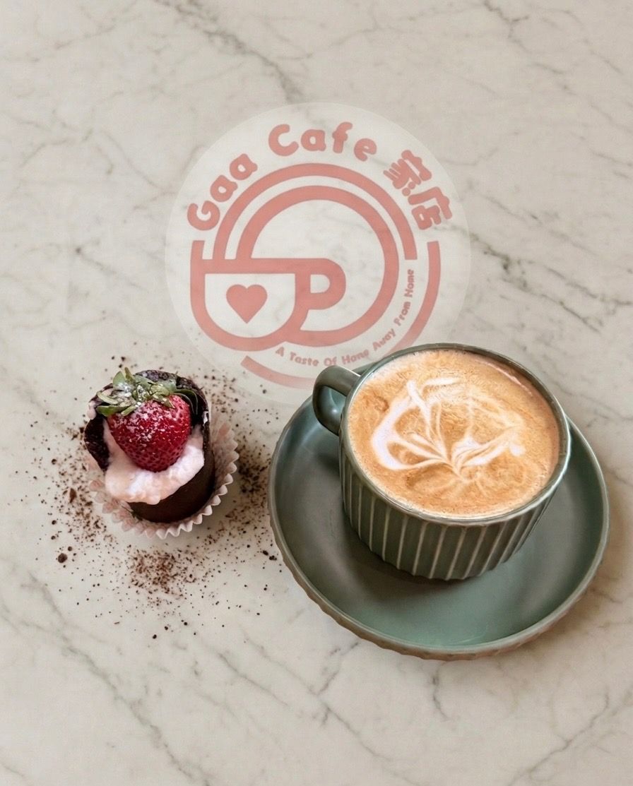 Coffee cup and berry dessert on a marble table with a pink cafe logo.