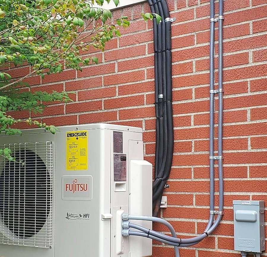 Fujitsu ductless mini-split outdoor unit installed by Lakeview beside a brick home