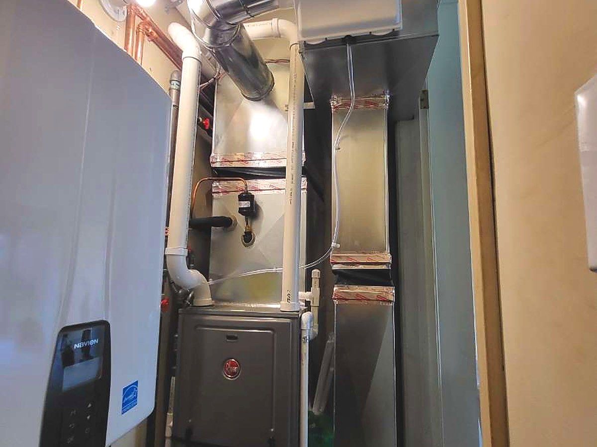Rheem gas furnace with humidifier and Navien tankless water heater installed in a utility closet by Lakeview