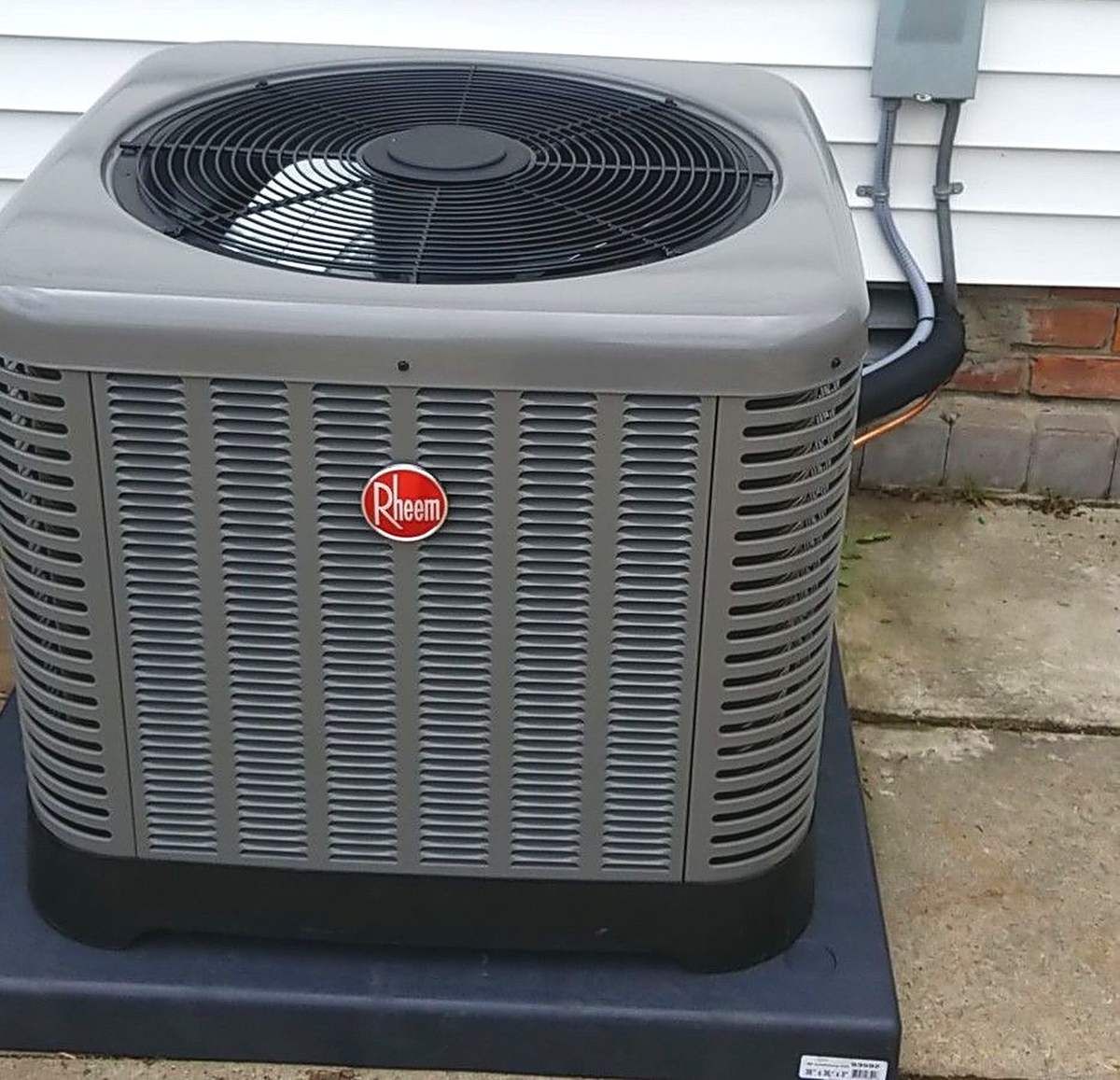 New Rheem central air conditioner on a new equipment pad beside a home, installed by Lakeview