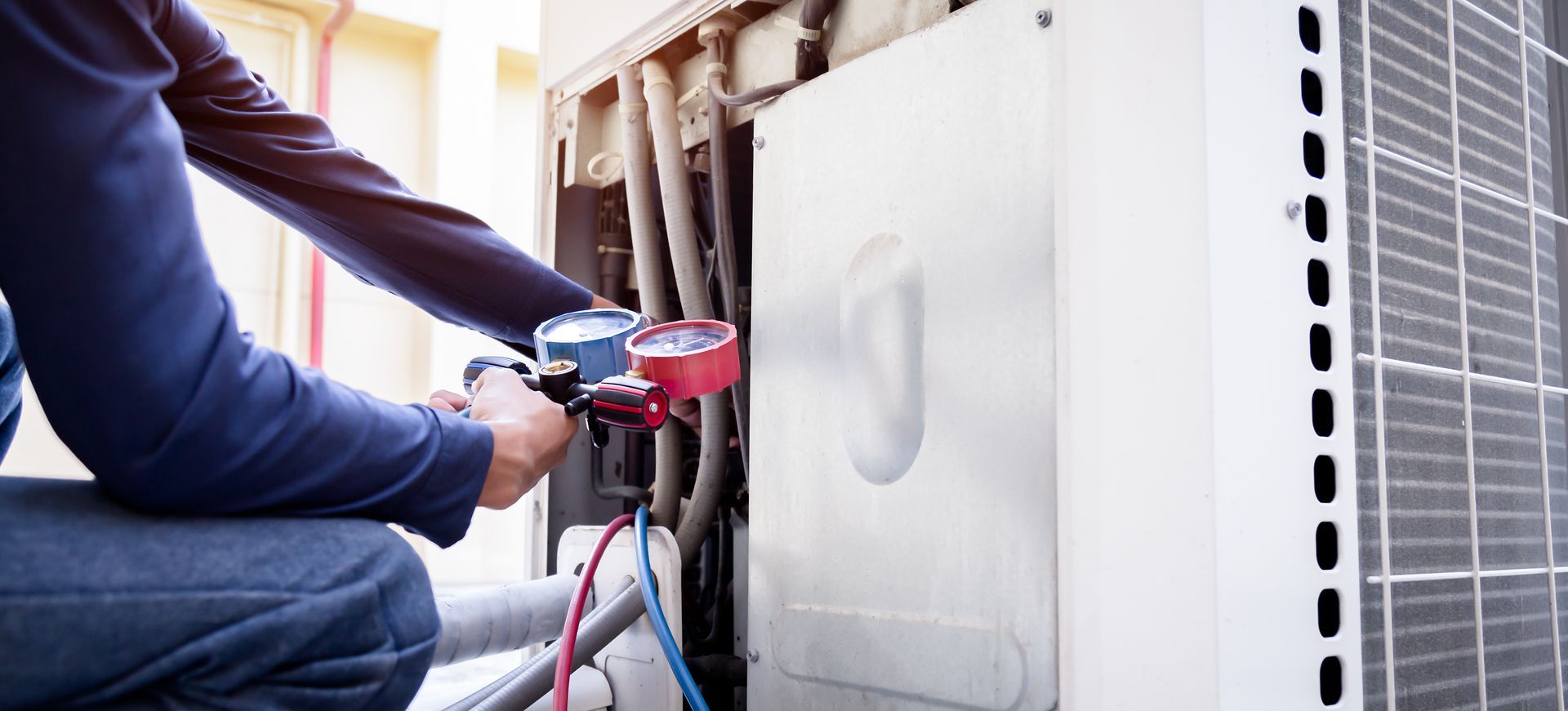 HVAC technician checking refrigerant pressure on an outdoor air conditioning unit HVAC technician checking refrigerant pressure on an outdoor air conditioning unit