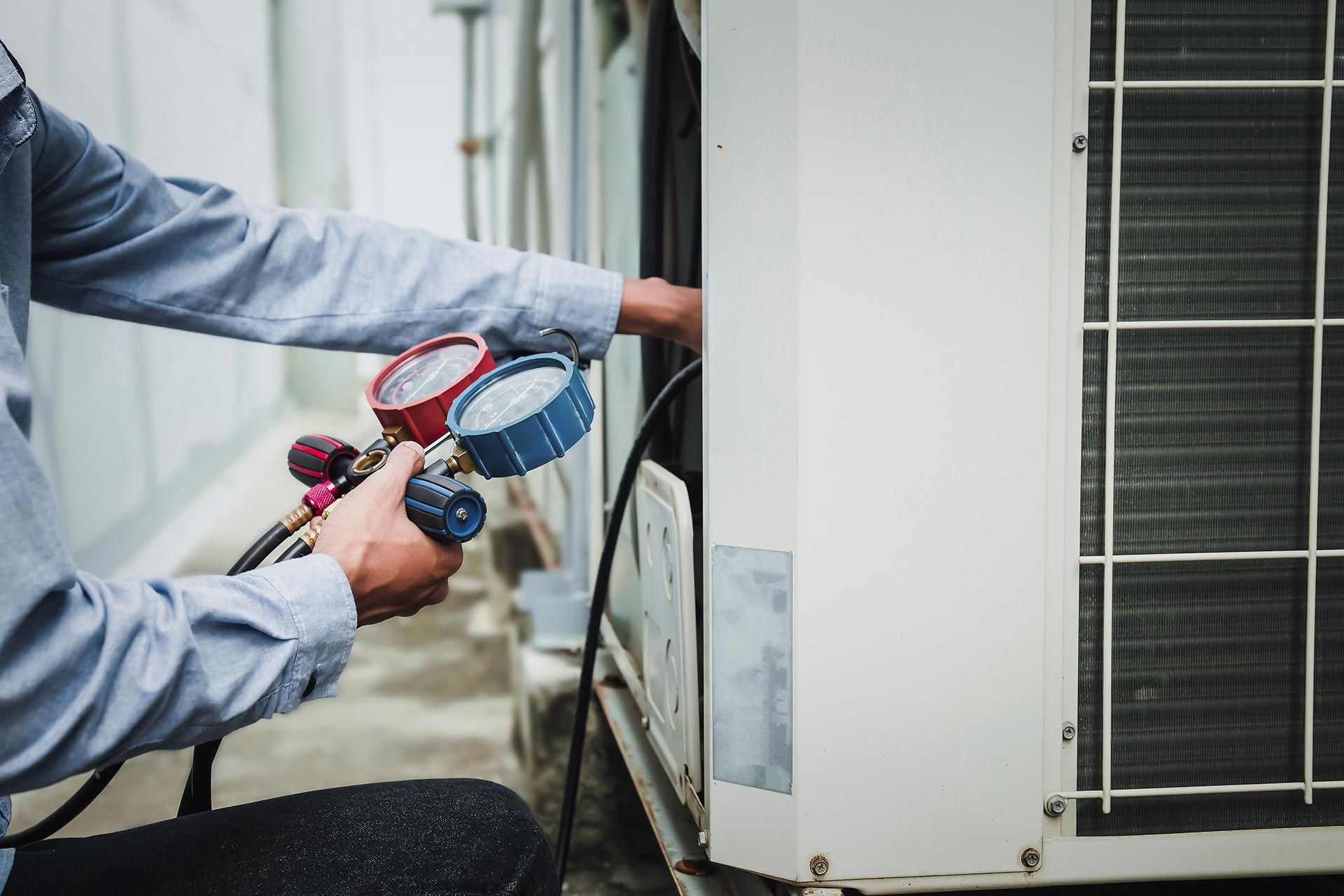 Mechanic air conditioner technician is using a manifold gauge to check the refrigerant in the system to inspect and repair the outdoor air Mechanic air conditioner technician is using a manifold gauge to check the refrigerant in the system to inspect and repair the outdoor air