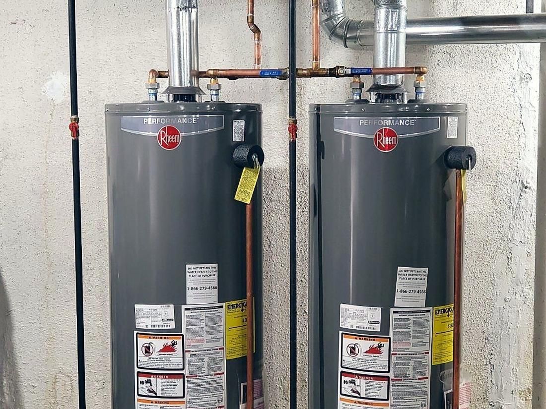 Two Rheem gas water heaters installed side by side with copper supply lines and flue venting by Lakeview in Warren, MI