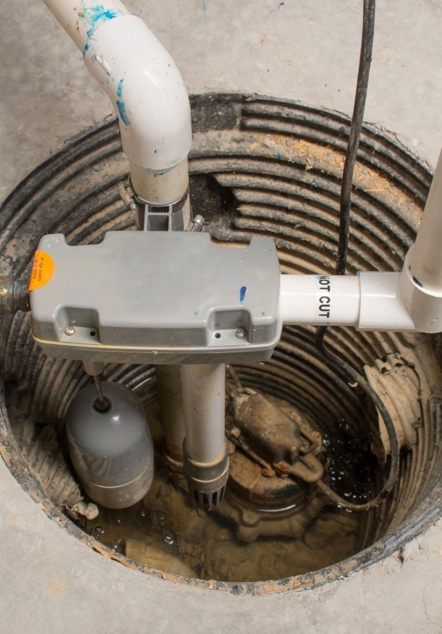 Sump pump, float switch and discharge piping inside an open sump pit in a basement floor