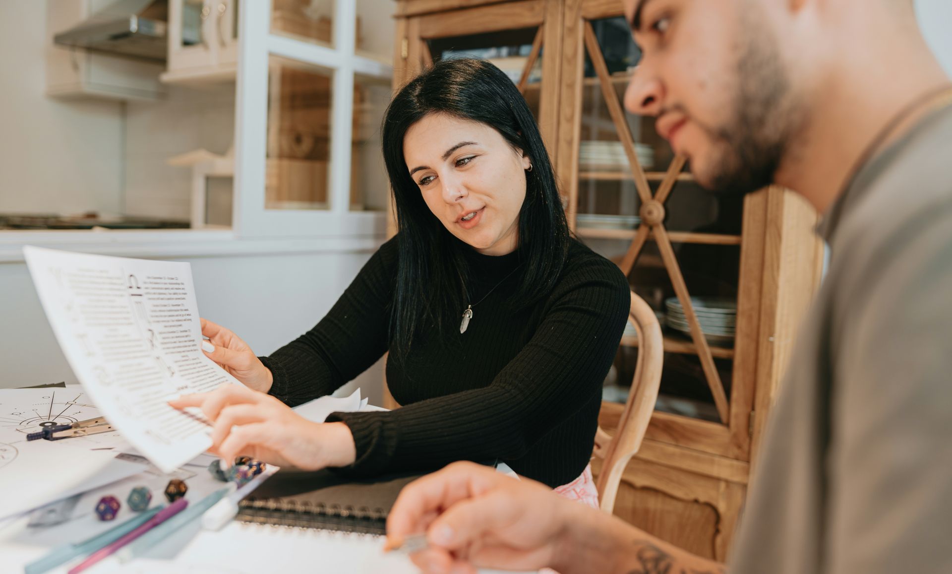 Two people reviewing a document together at a table in a bright office, pointing at the page.