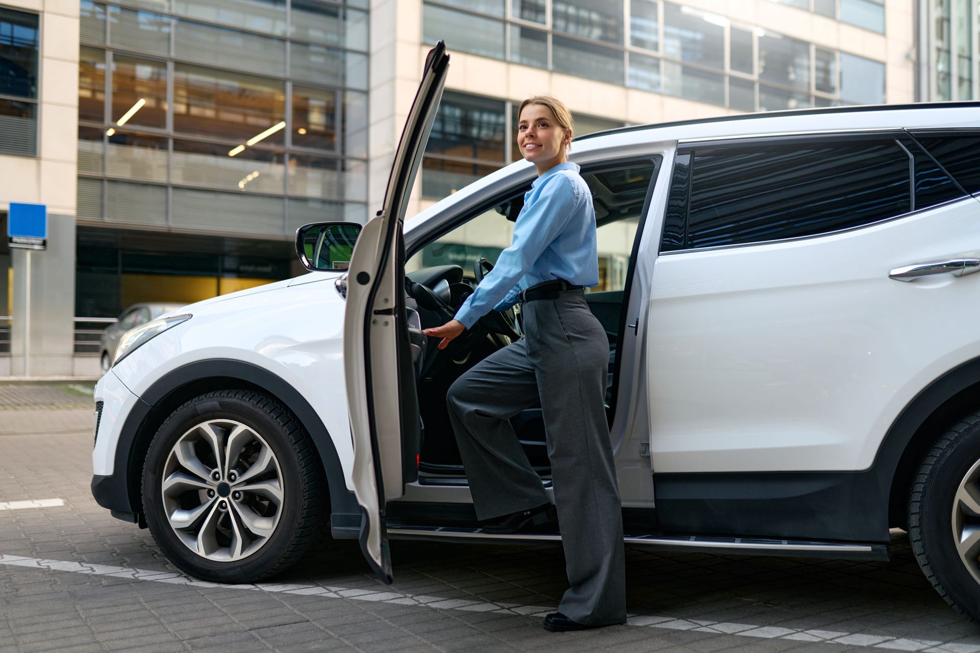 Woman stepping out of a white SUV in front of an office building.