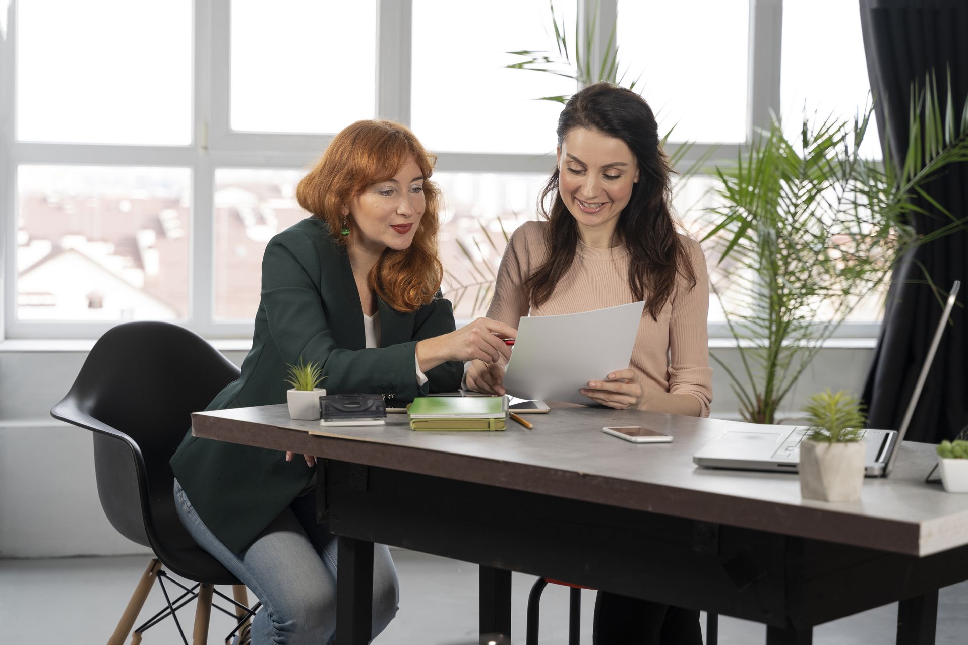 Two coworkers reviewing a document together at a desk in a bright office