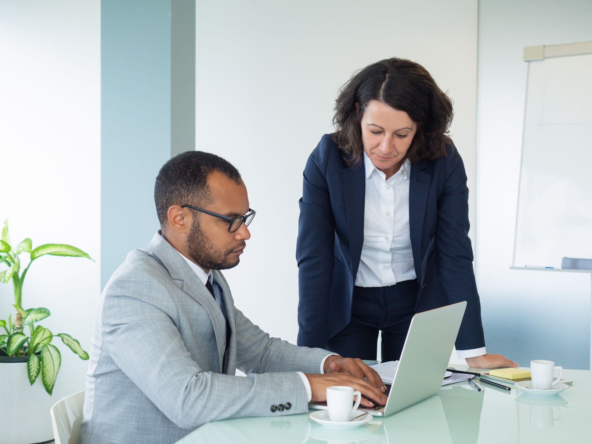 Two colleagues reviewing a laptop in a bright office meeting room
