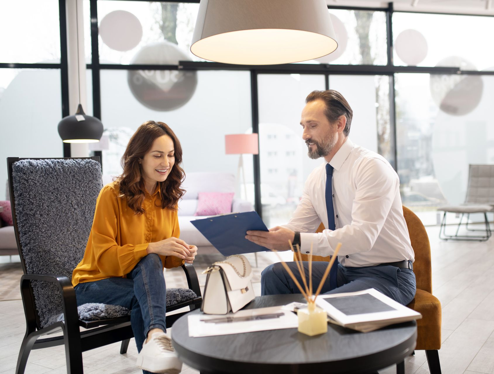 Two coworkers discussing a blue folder in a bright modern office lounge
