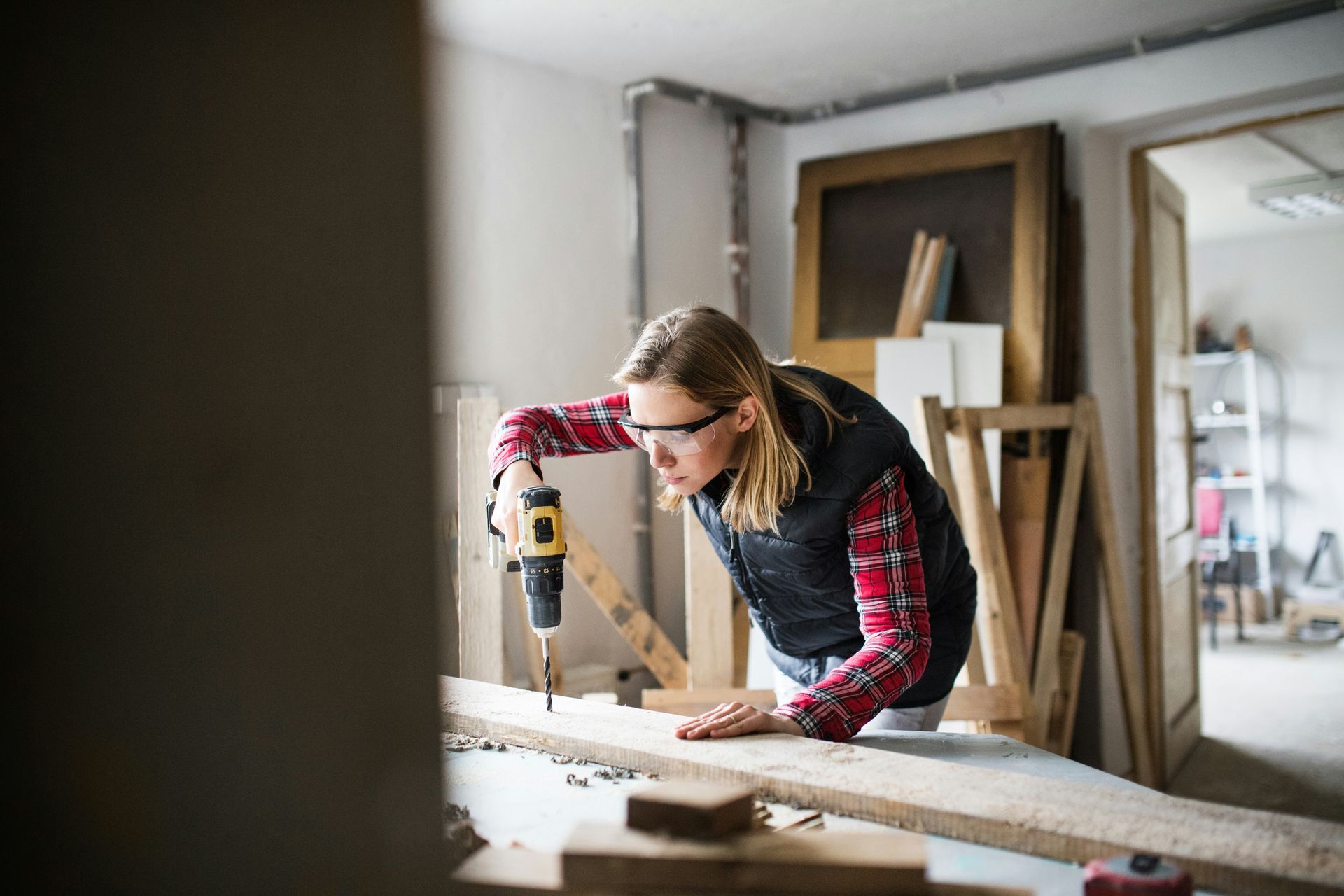 Person using a power drill while building a wooden project in a workshop