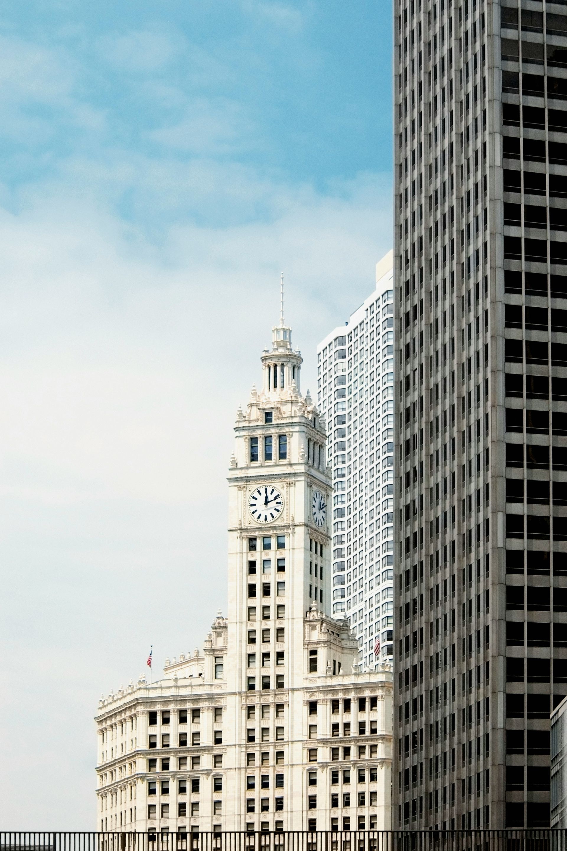 Tall historic white building beside a dark modern skyscraper under a blue sky