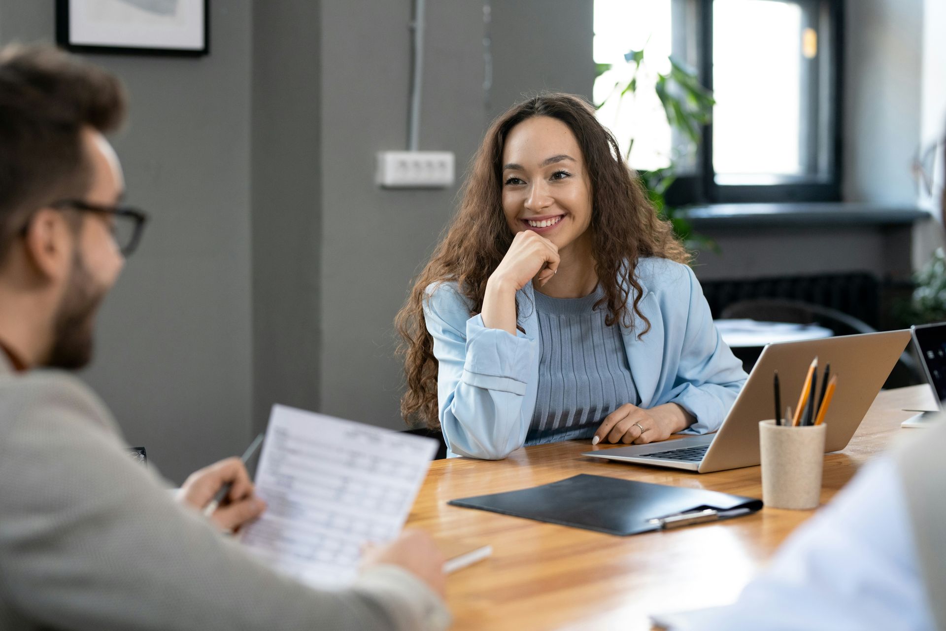 Woman and man reviewing documents at a desk in an office with plants and a computer.