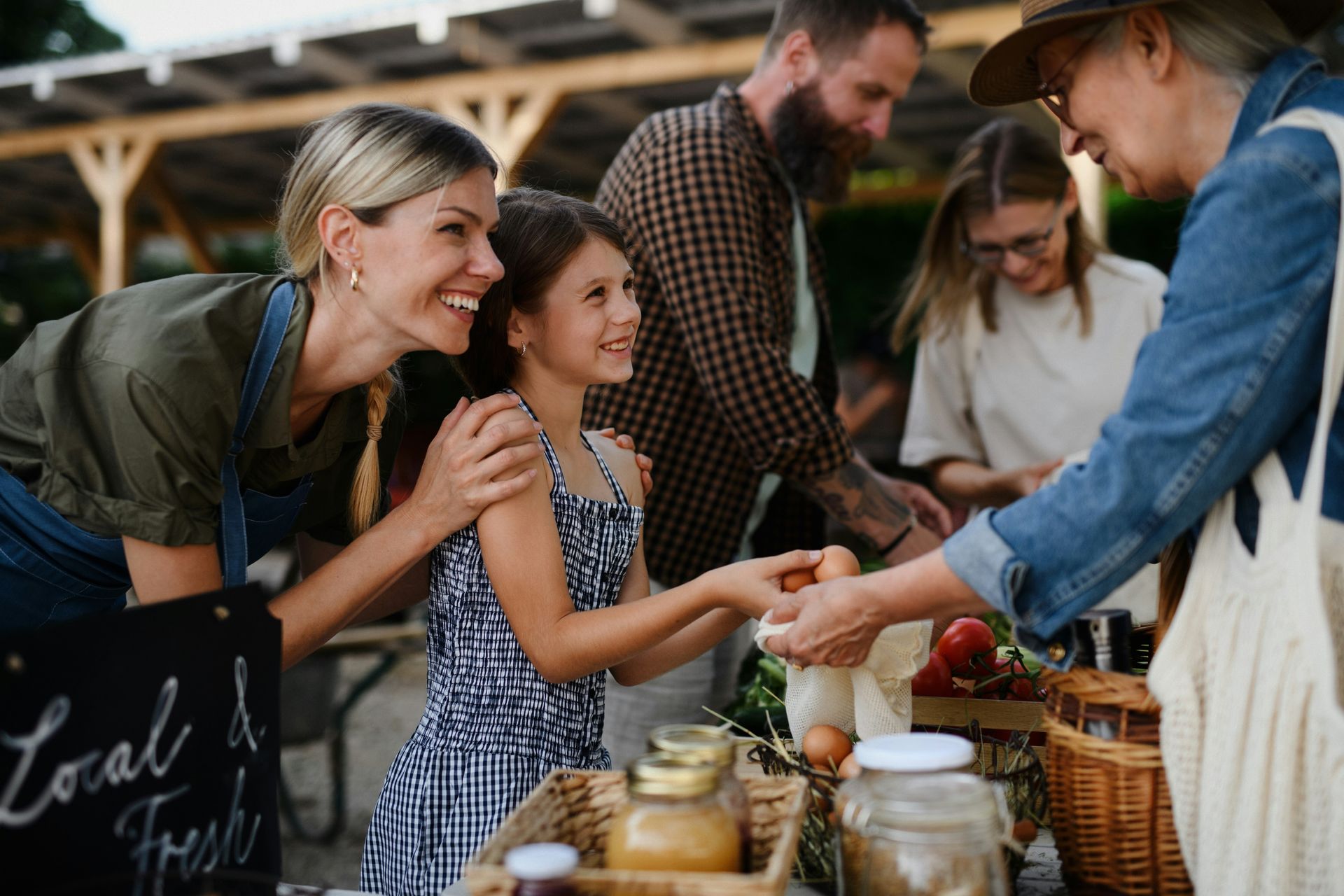 People sampling goods at a market stall with jars and baskets