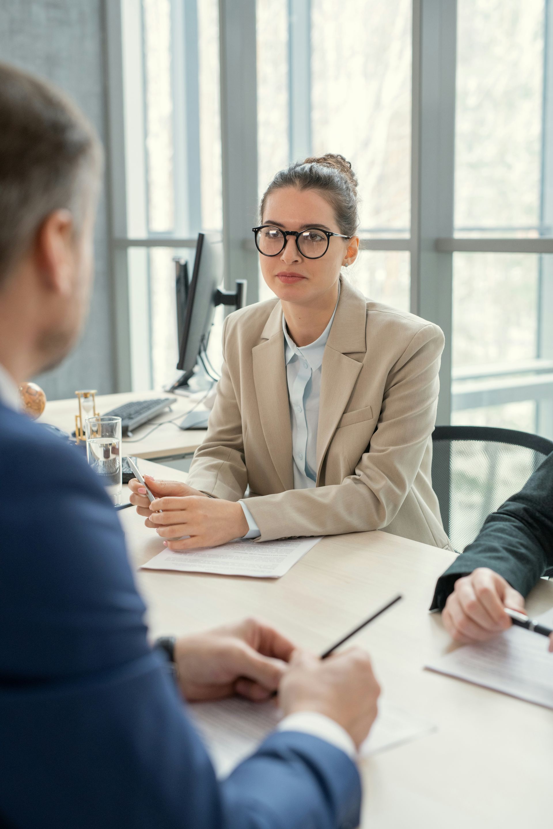 Business meeting in a bright office, with people discussing around a conference table.