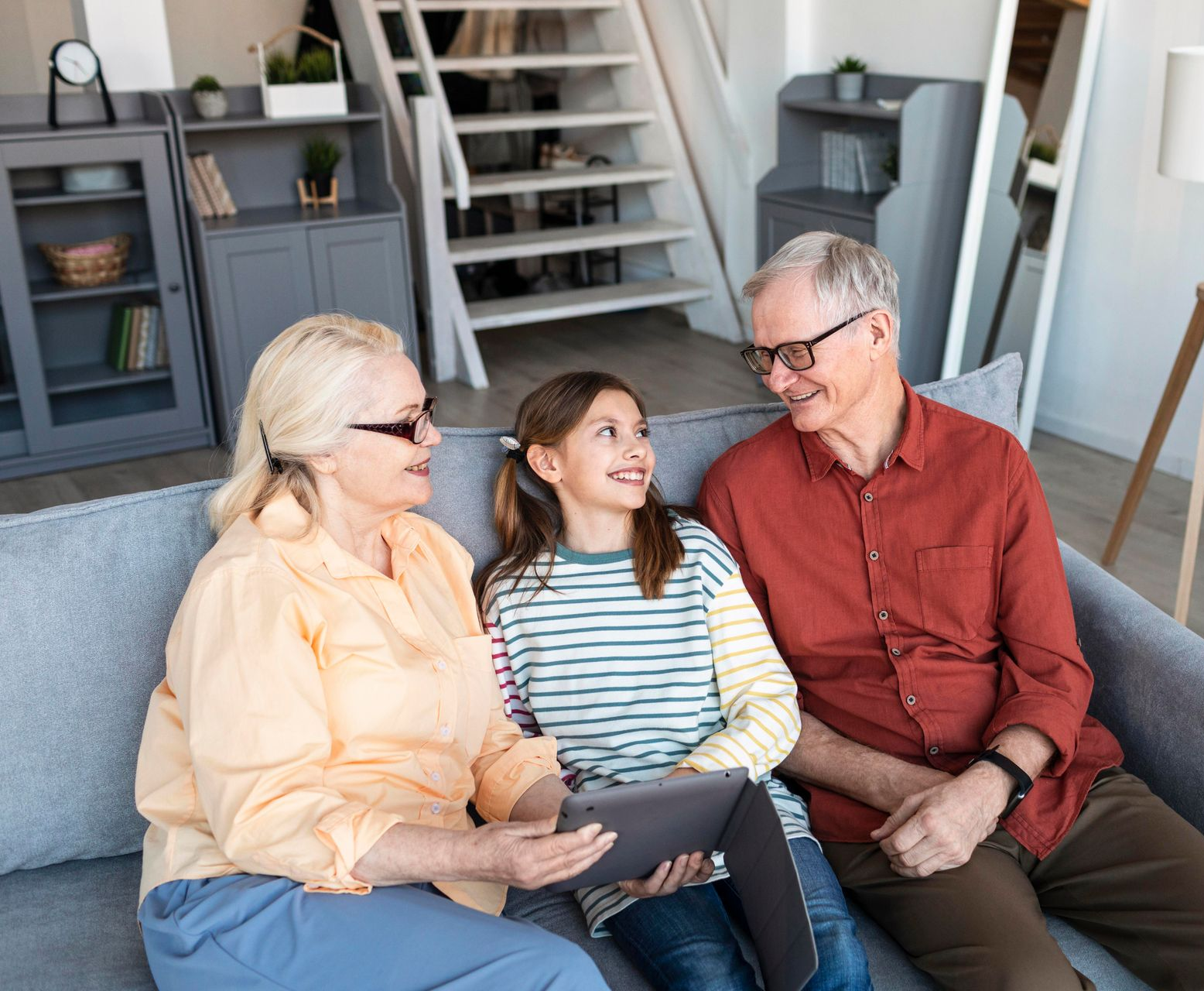 Three people sitting on a couch, smiling and talking in a bright living room