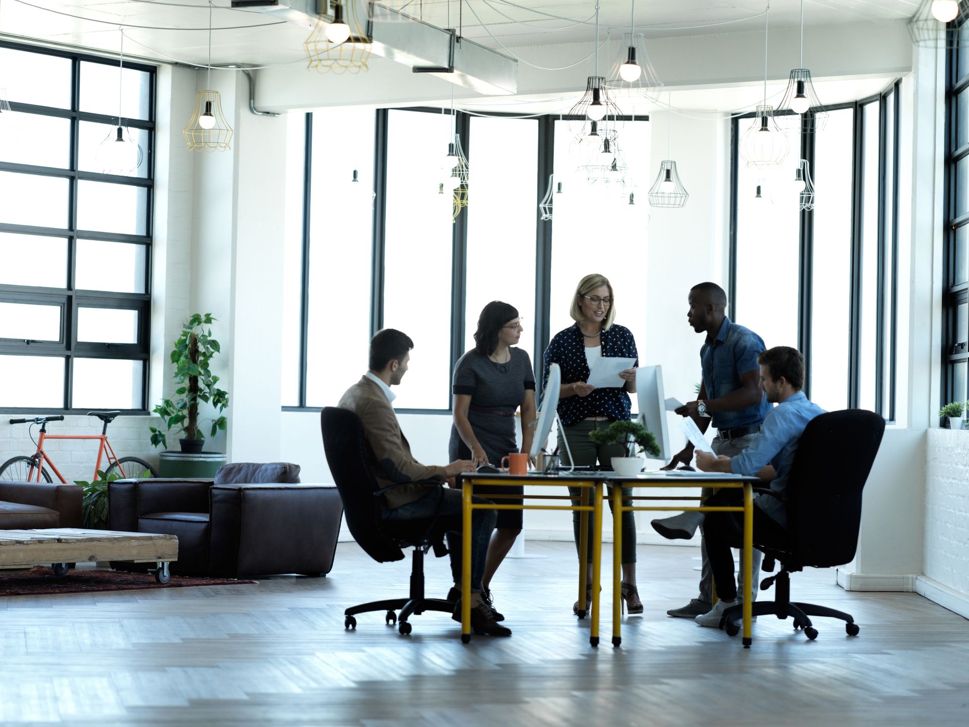 People gathered around a table in a bright office meeting room with large windows.
