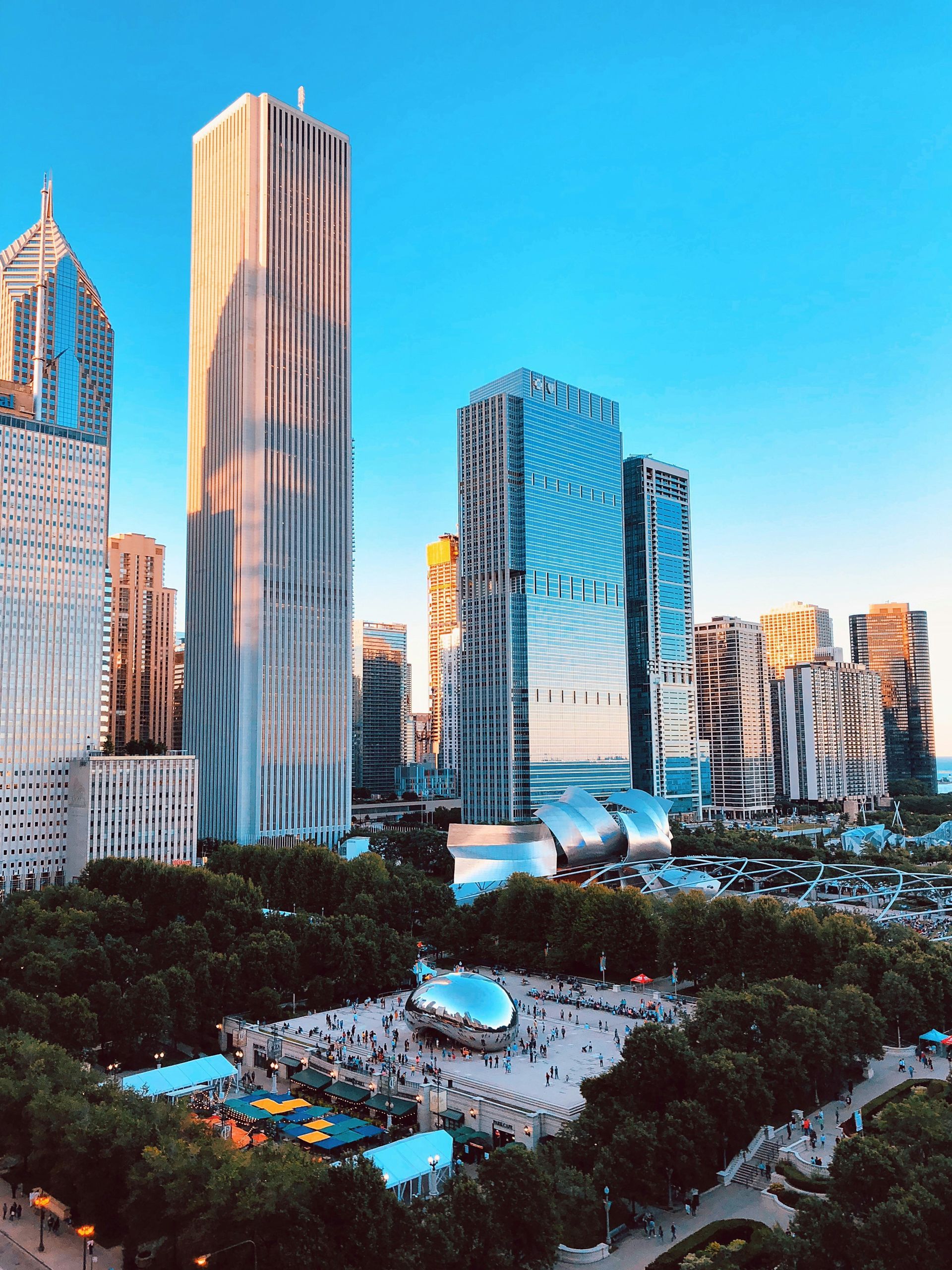 Downtown skyline with tall modern glass skyscrapers and a green park under a bright blue sky