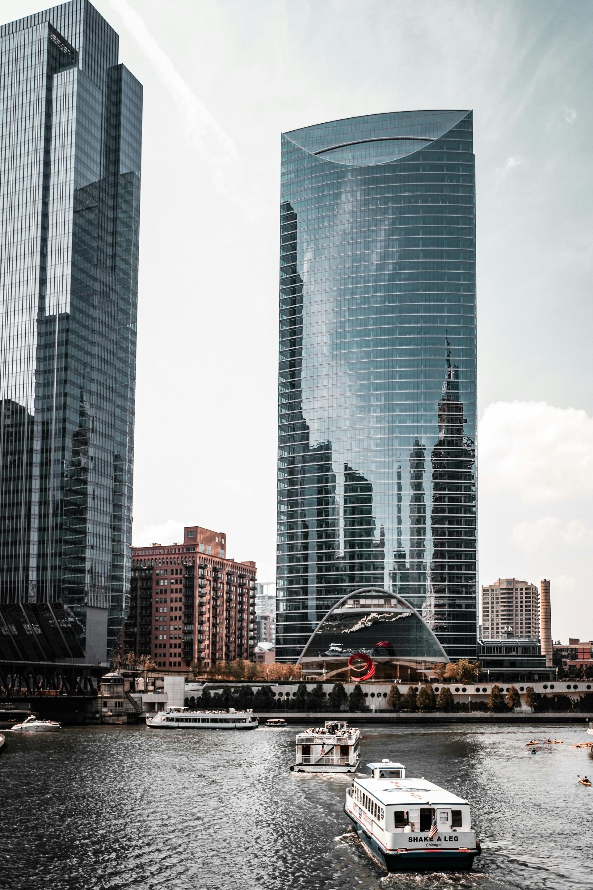 Modern glass skyscrapers along a waterfront, with a small boat in the foreground