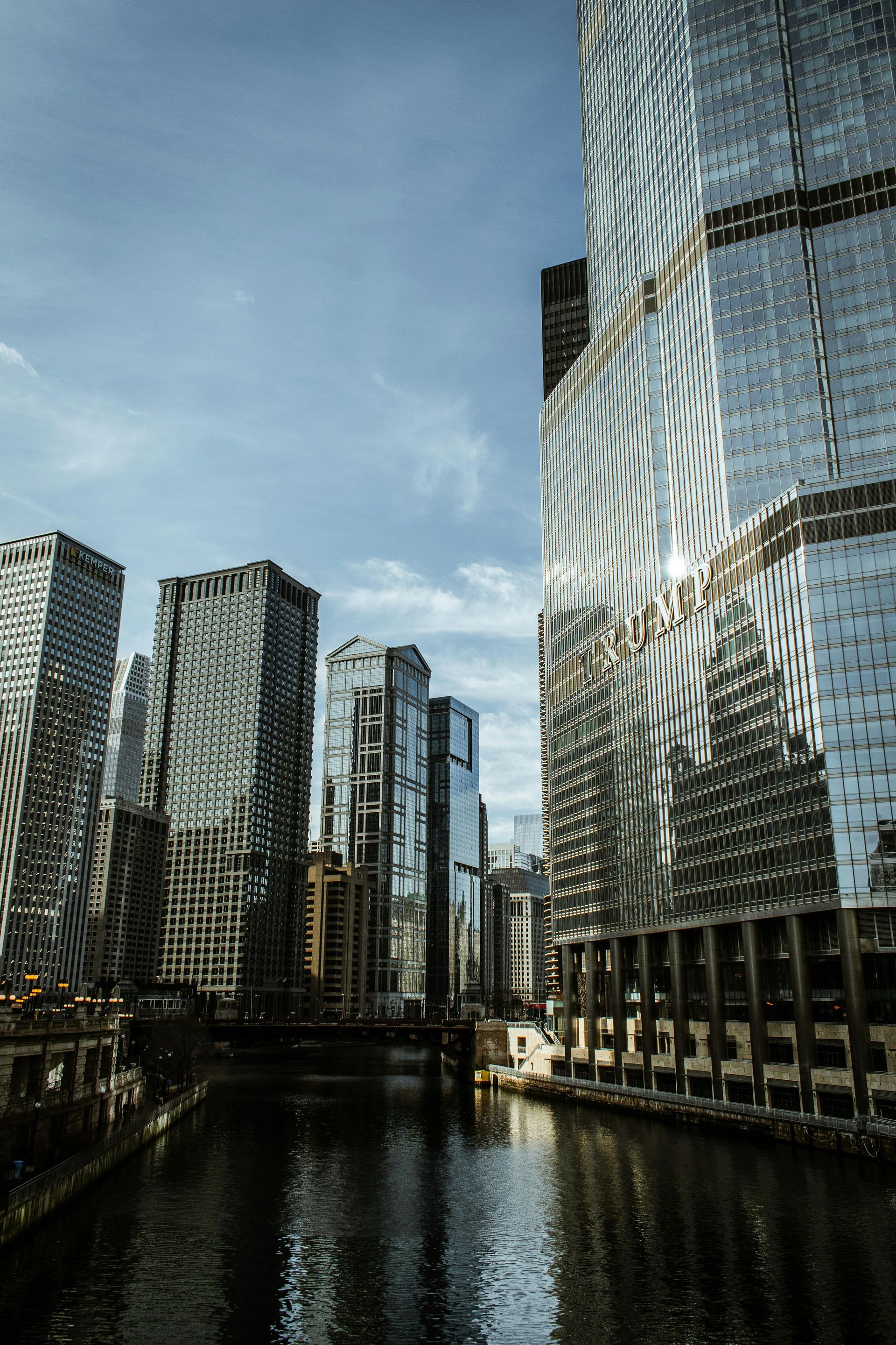 Modern glass skyscrapers lining a canal under a cloudy sky