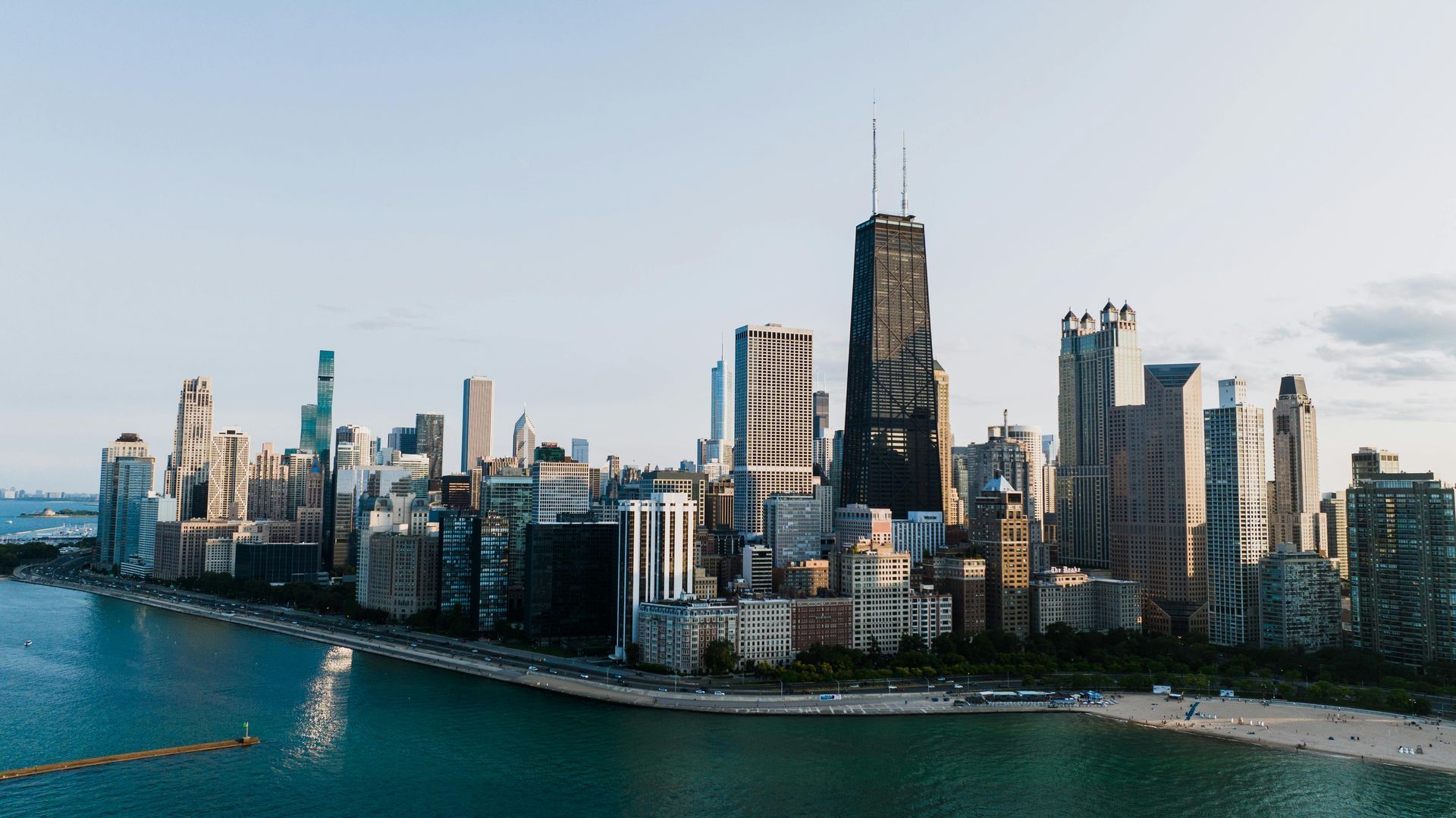 City skyline with tall modern buildings along a waterfront under a clear sky