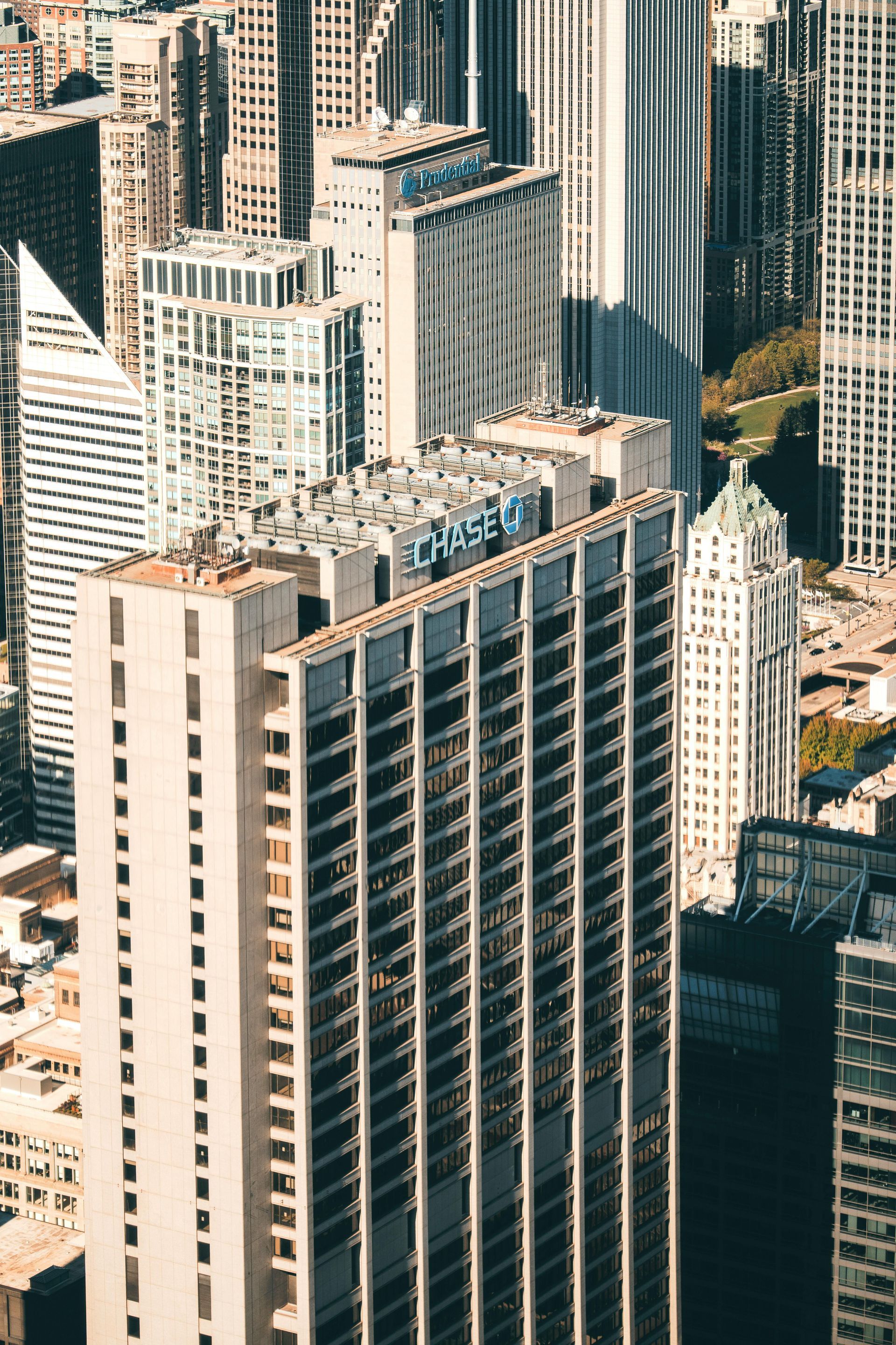 Tall white high-rise hotel amid dense city skyscrapers, viewed from above.