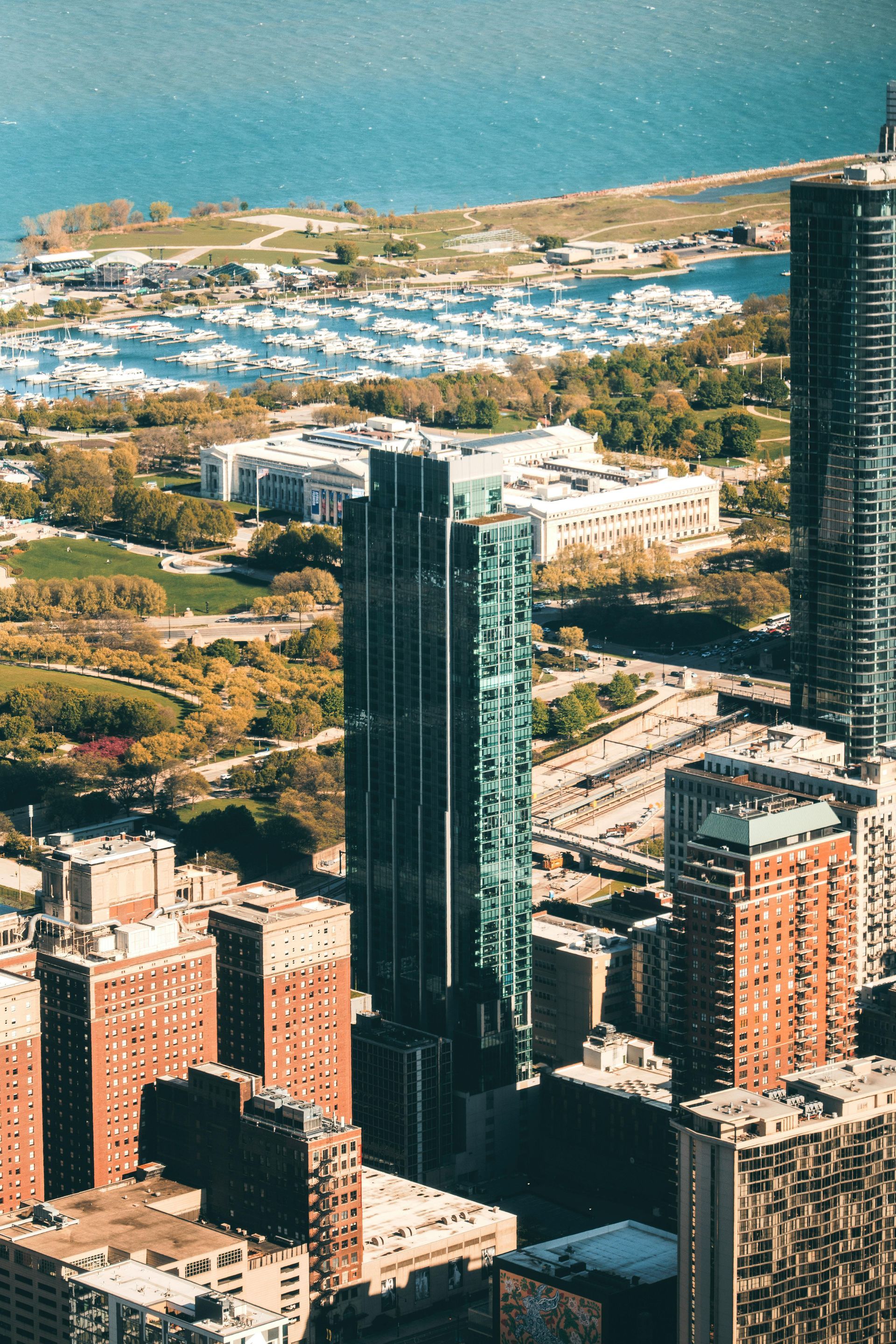 Aerial view of tall city skyscrapers beside a blue waterfront and harbor.