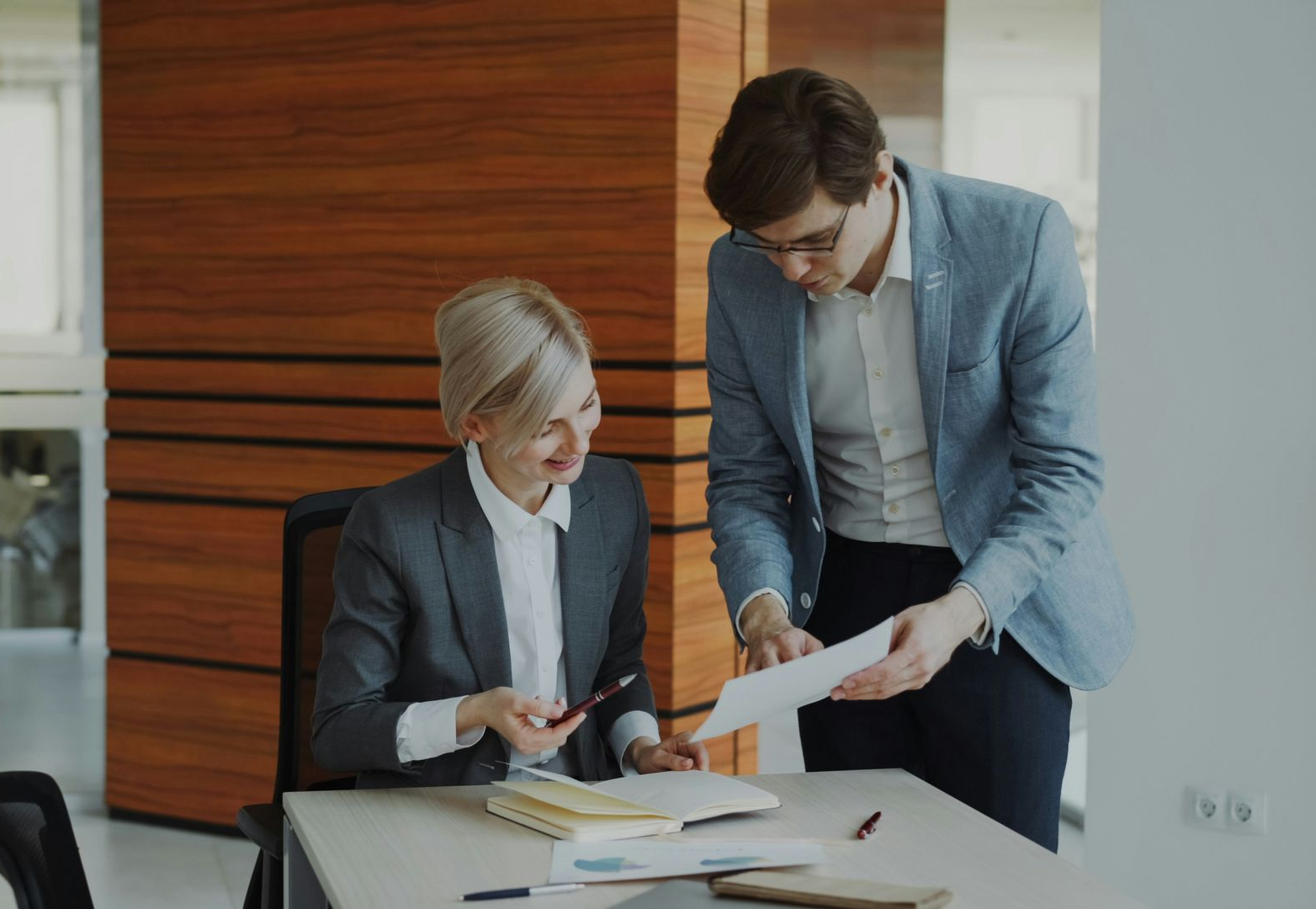 Two businesspeople reviewing documents at a desk in a bright office