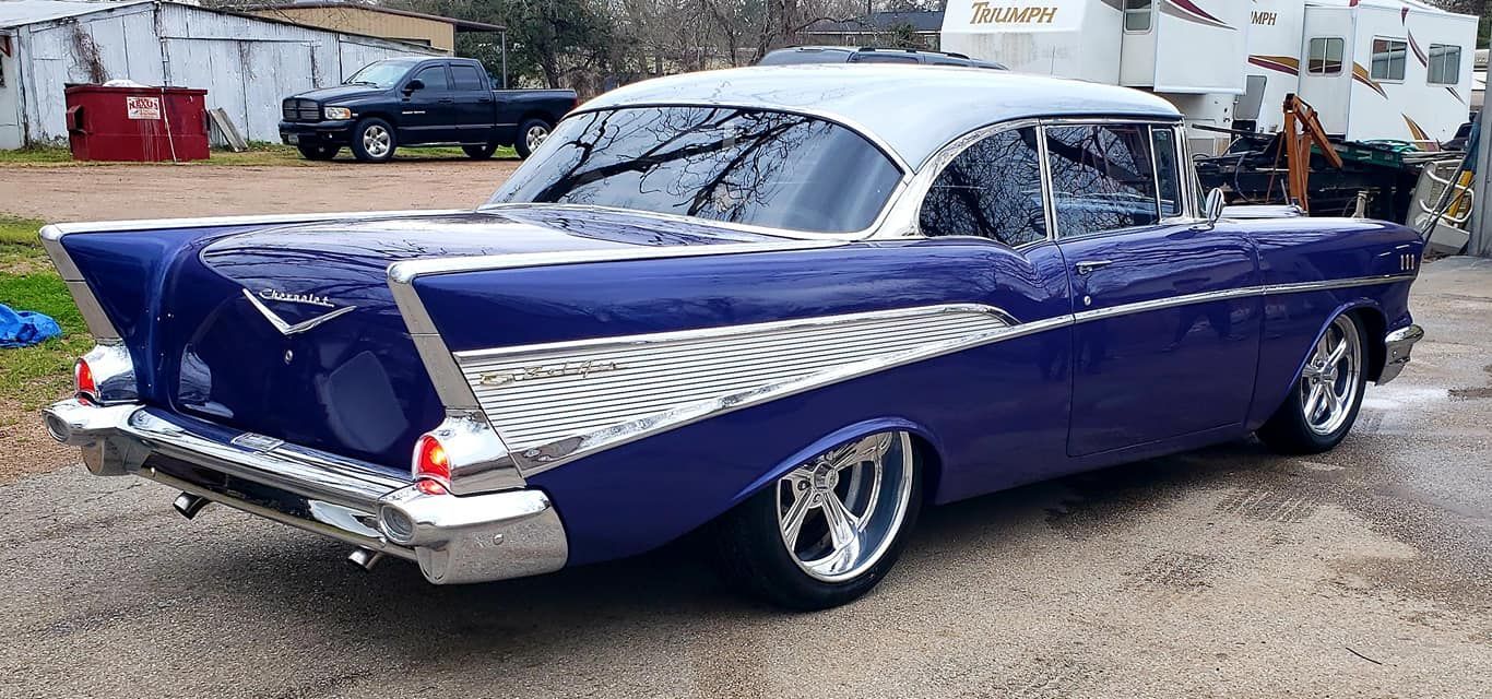 Blue and white classic car parked on a paved lot.