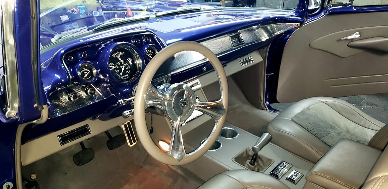 Blue classic car interior with chrome accents, tan leather, and custom steering wheel.