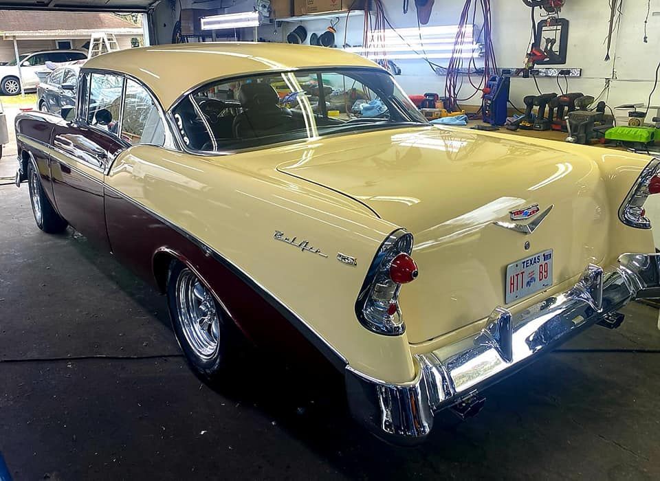 Two-tone cream and burgundy 1956 Chevrolet Bel Air in a garage.
