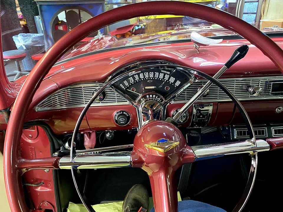 Red classic car interior with steering wheel, dashboard, and chrome accents.