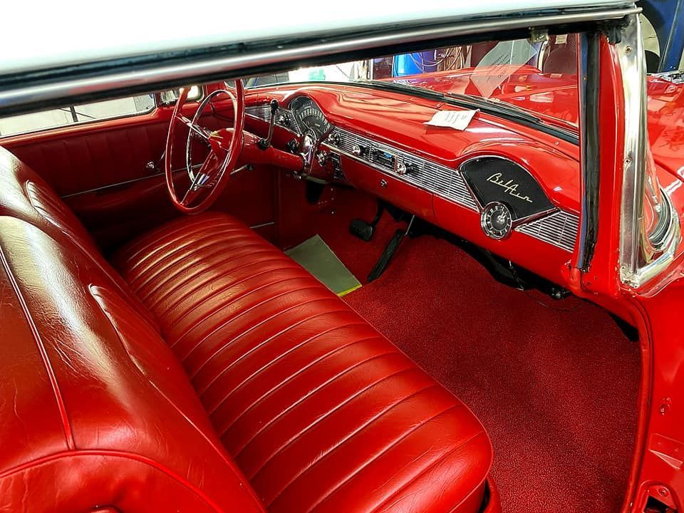 Red interior of a classic Chevrolet Bel Air, featuring red seats, dashboard, and carpet.