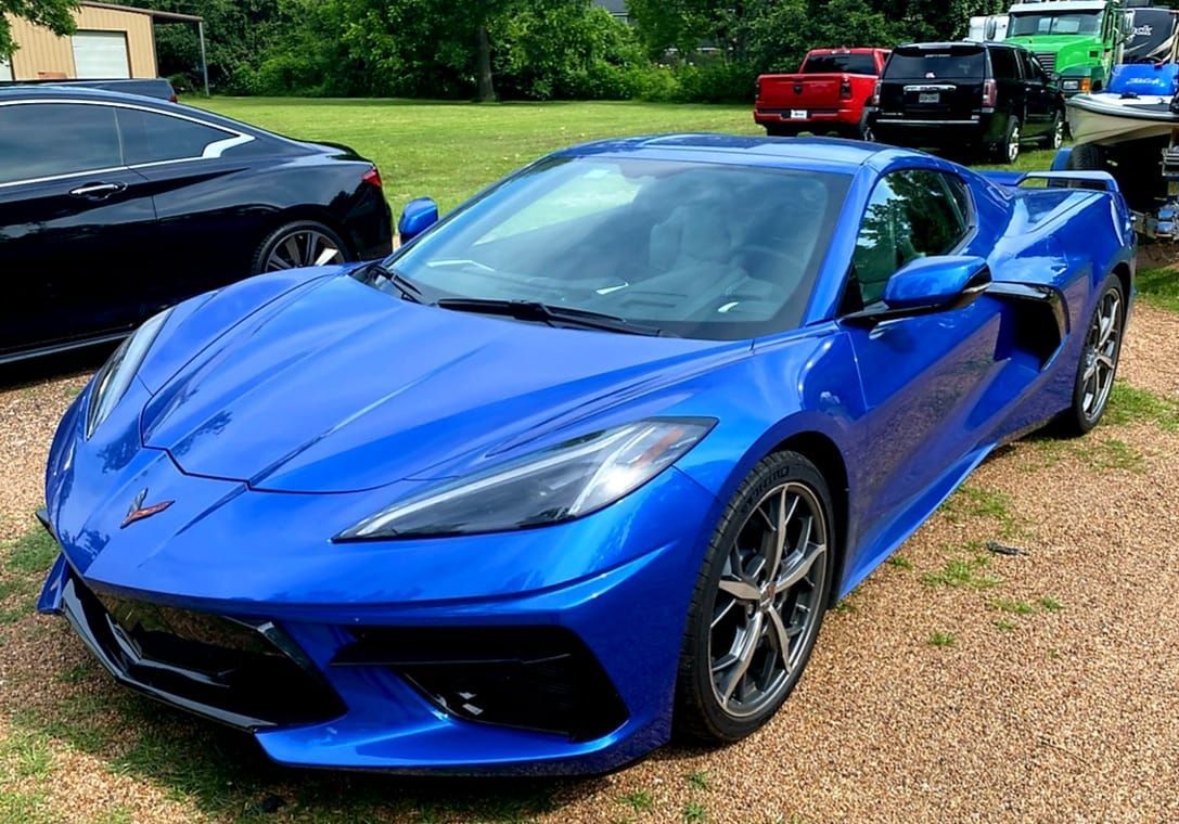 Blue Chevrolet Corvette sports car parked on grass.