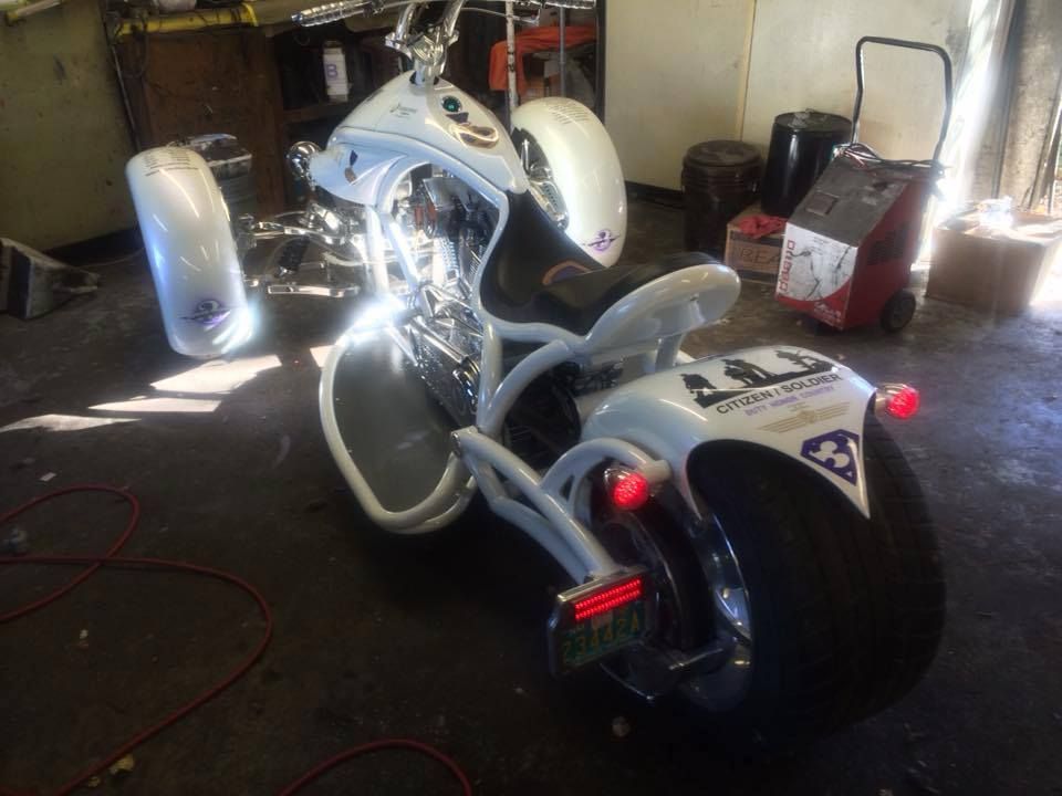 Custom white three-wheeled motorcycle in a garage.