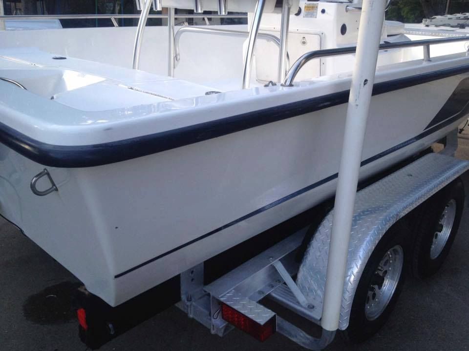 White fishing boat on a trailer, black trim, parked outside.