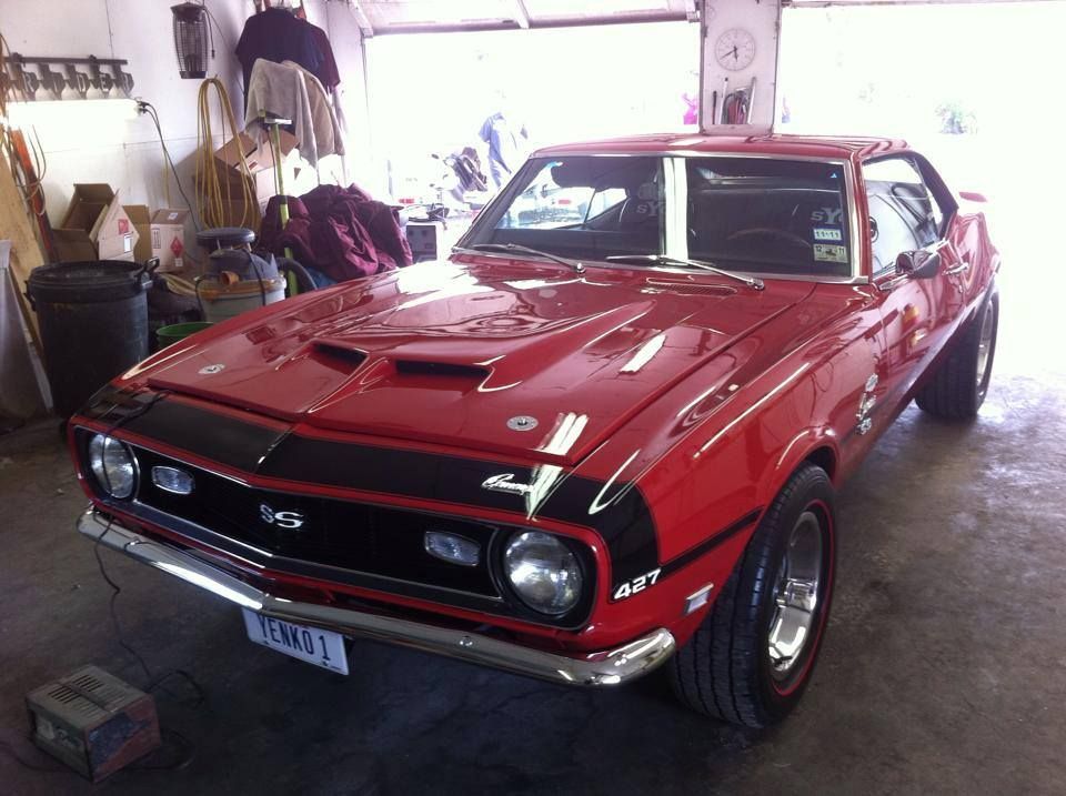 Red 1968 Chevrolet Camaro SS, black racing stripes, in a garage.
