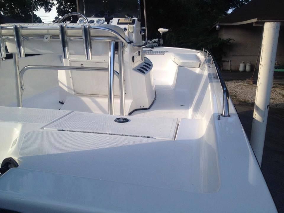 White boat deck with console, railing, and storage compartment.