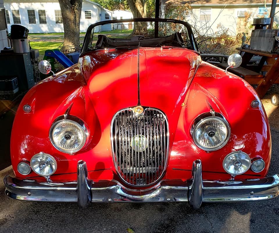 Red Jaguar convertible with chrome details, parked in front of a house.
