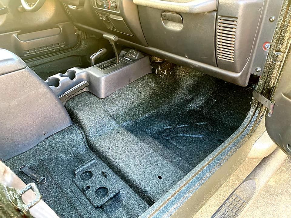 Jeep interior with black flooring and center console, showing driver's side and passenger footwell.