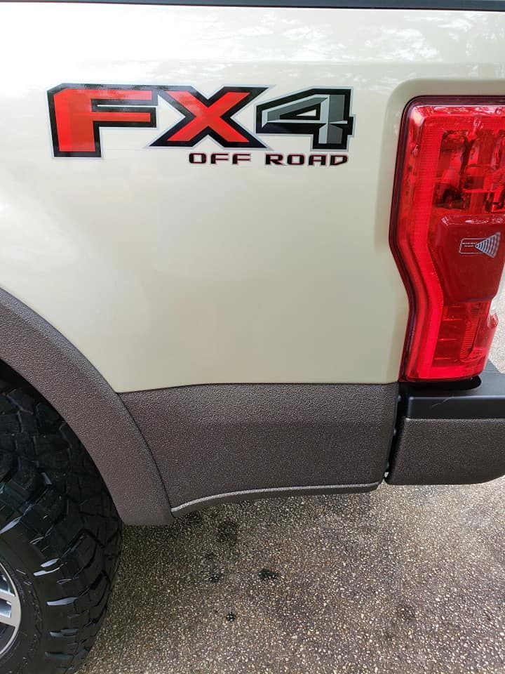 White truck bed with FX4 Off Road emblem, brown textured trim, and red taillight.