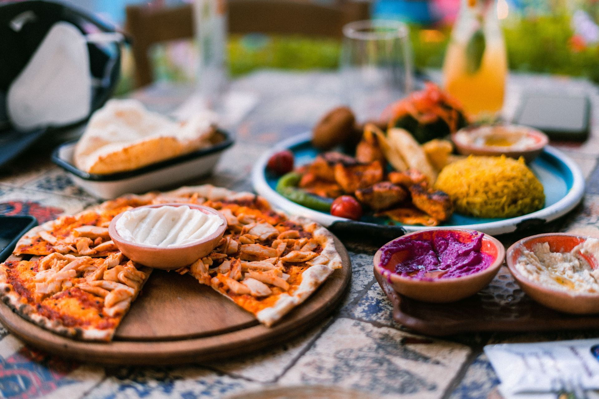 Surtido de mezze y salsas sobre una mesa, con pan plano, arroz, verduras asadas y pequeños cuencos de salsas.