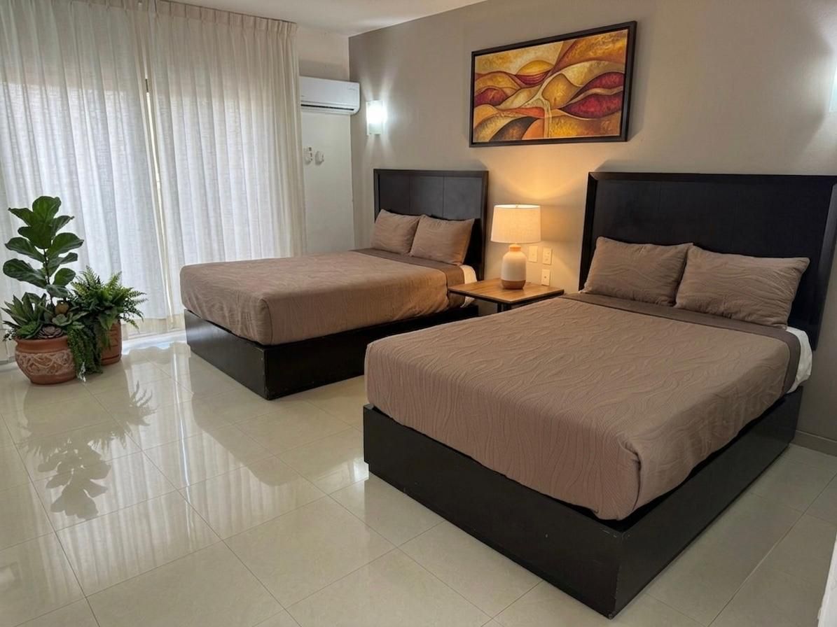 Habitación de hotel moderna con dos camas individuales, lámpara de noche, cuadros en la pared y cortinas de colores vivos.