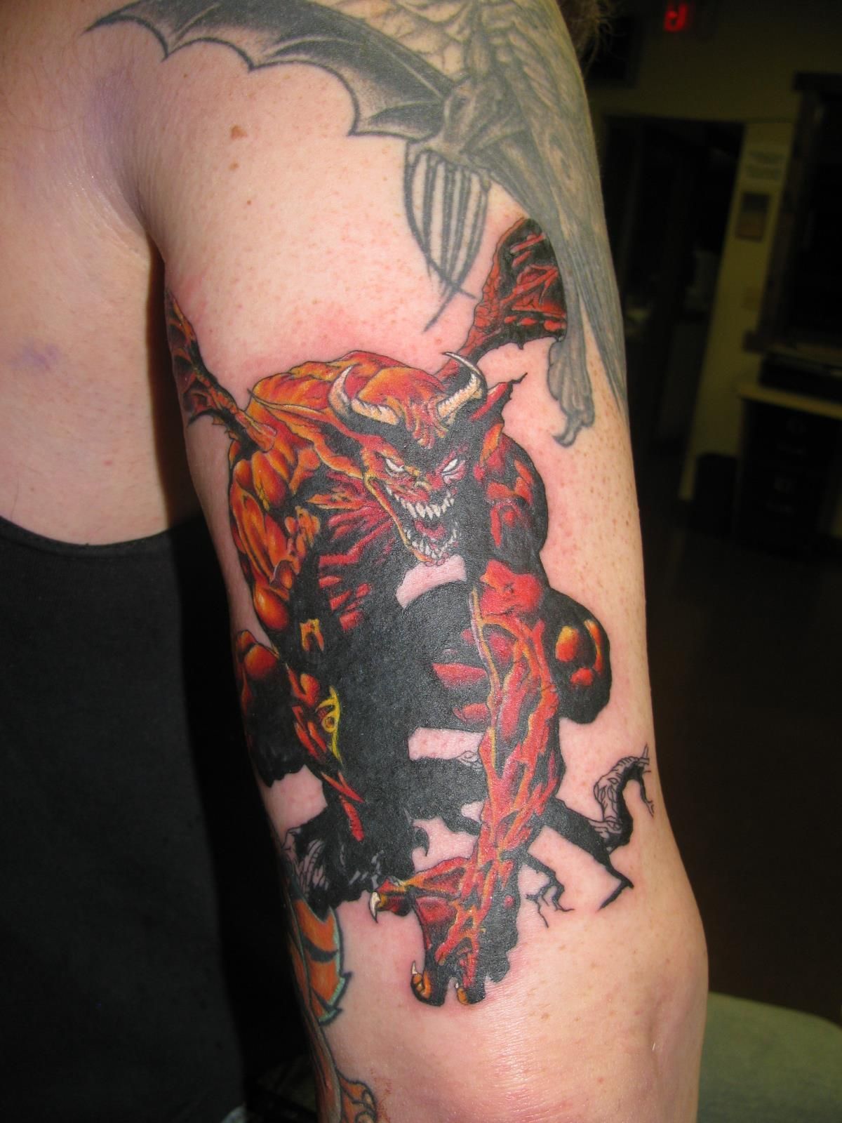 Close-up of a colorful red and black tattoo on an upper arm and shoulder