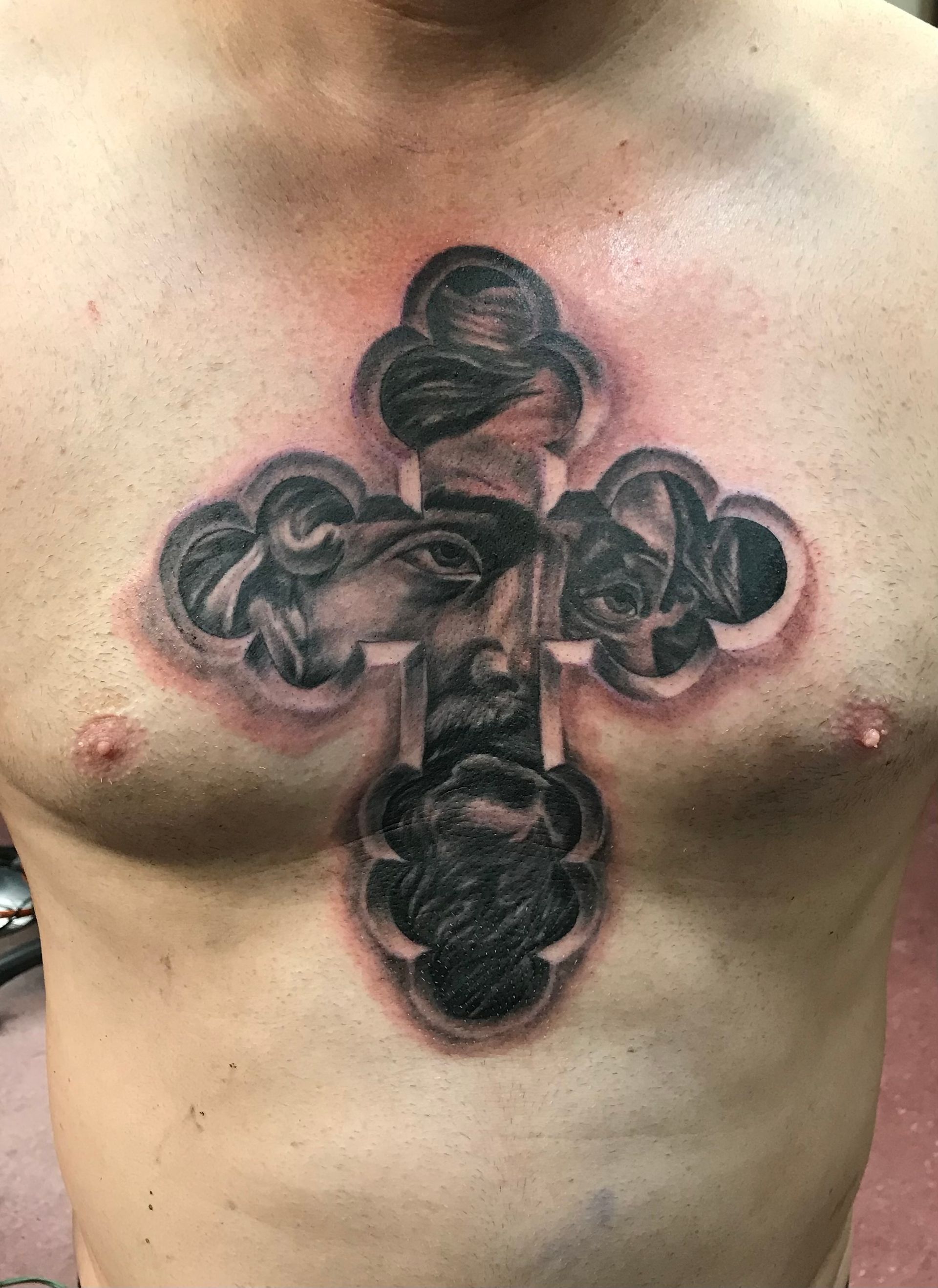 Torso with a large black cross tattoo across the chest, centered on the sternum.