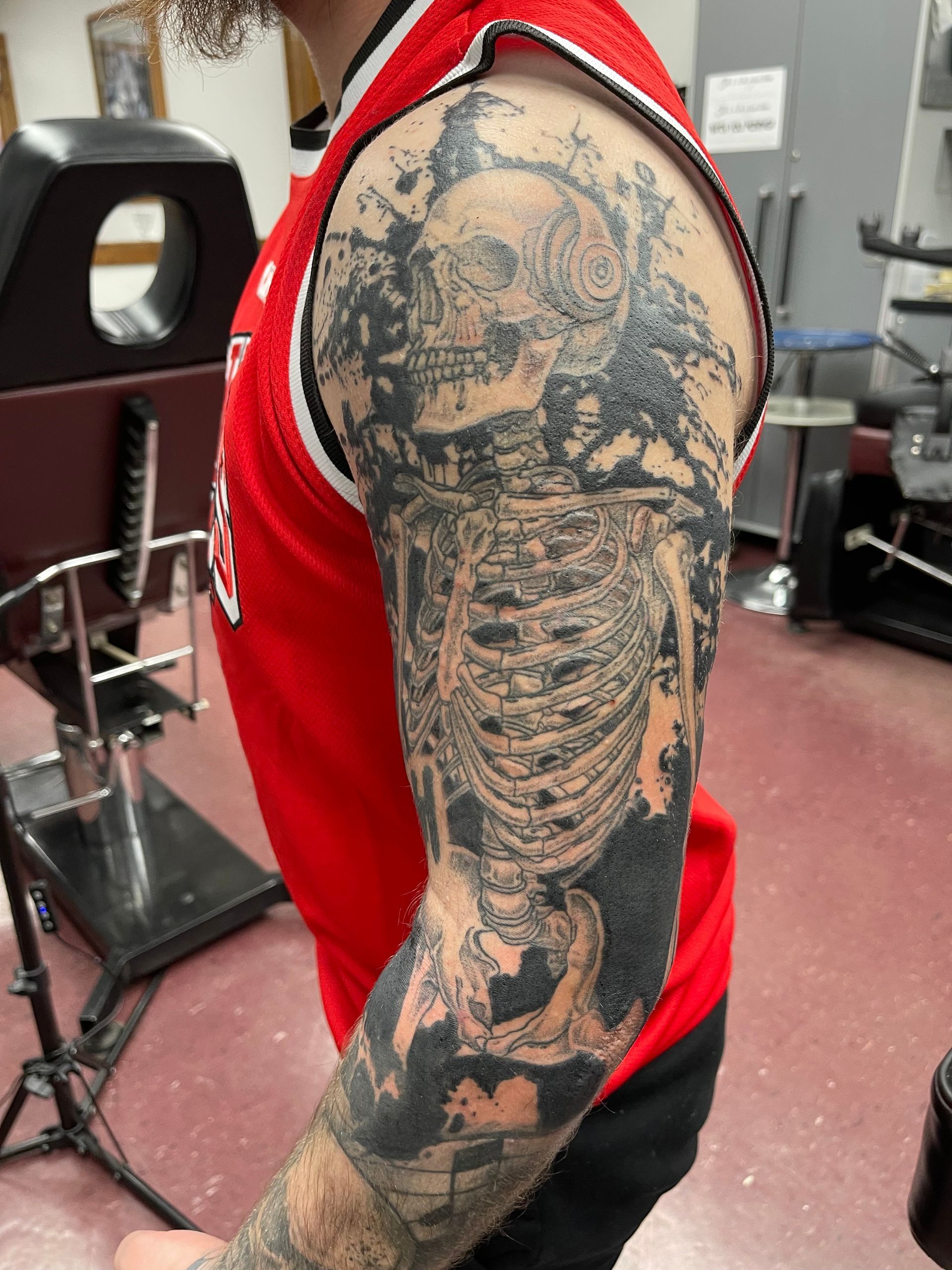 Close-up of a person’s arm tattoo showing a detailed skeleton design in a tattoo studio.