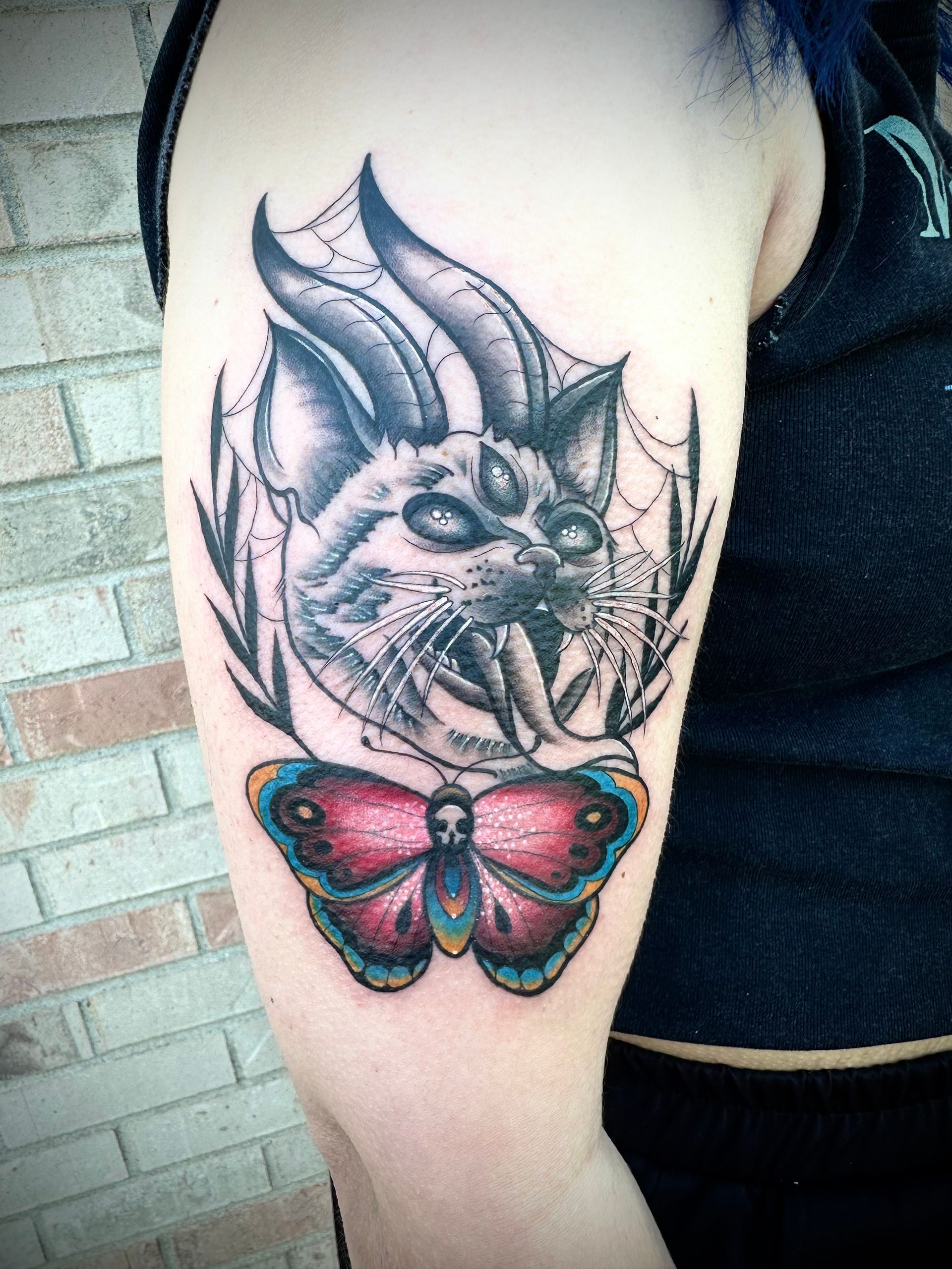 Arm tattoo of a snarling wolf above a colorful butterfly on an upper arm