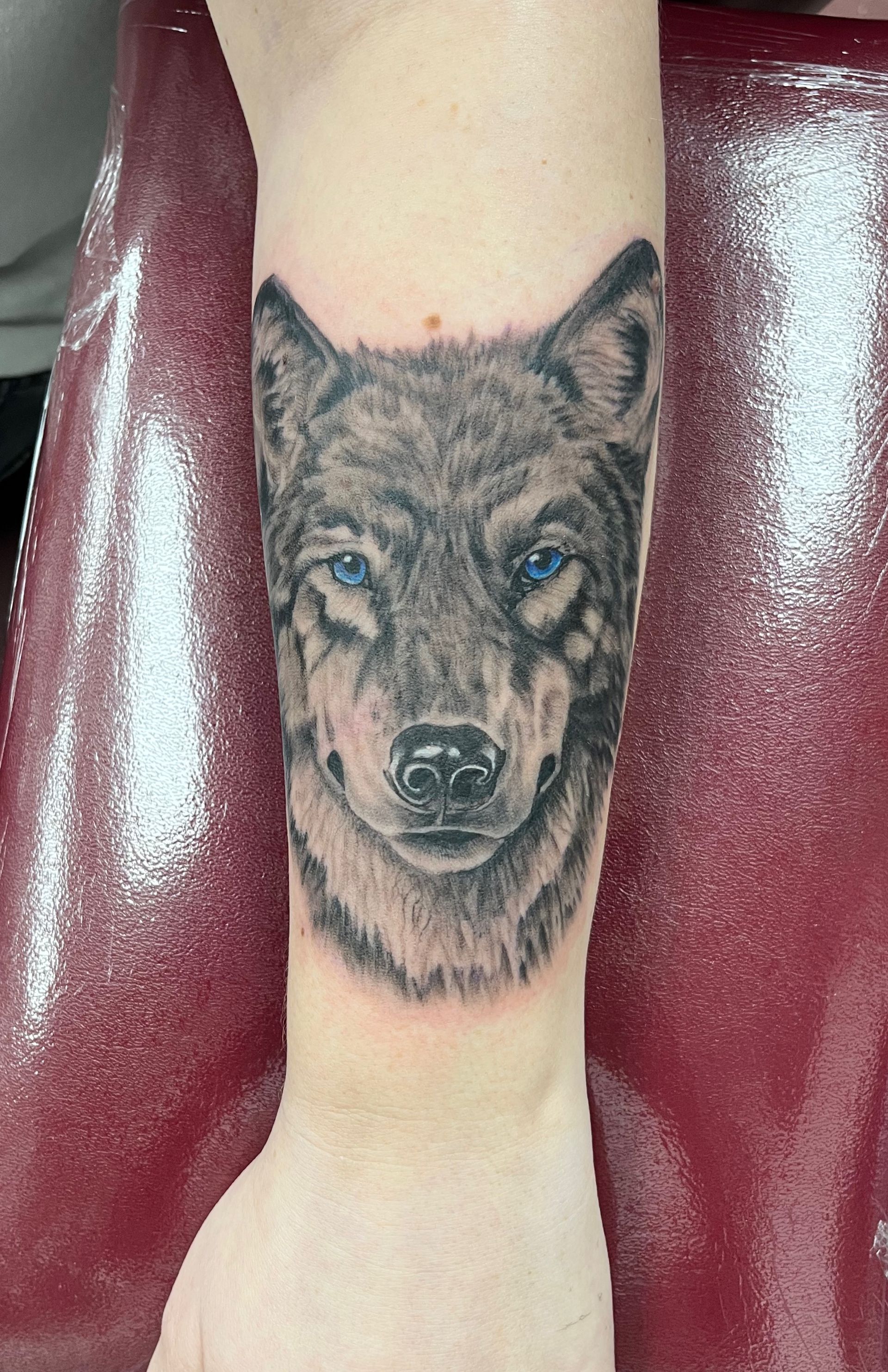 Realistic wolf head tattoo on a person’s calf, centered on the leg