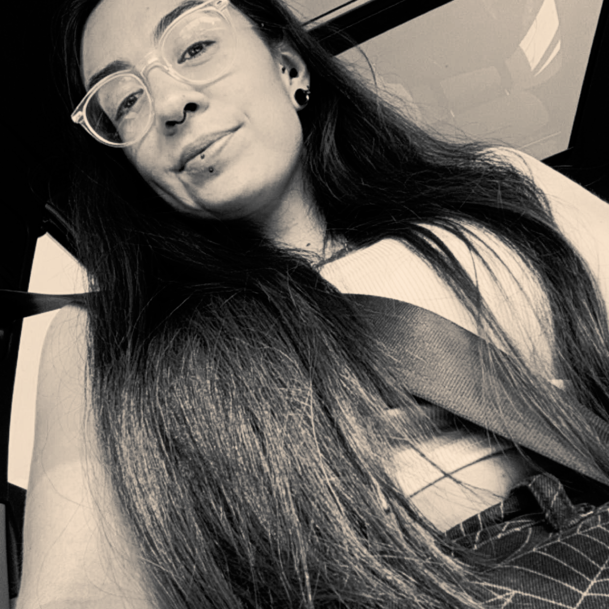 Person with glasses and long hair posing in a black-and-white selfie.