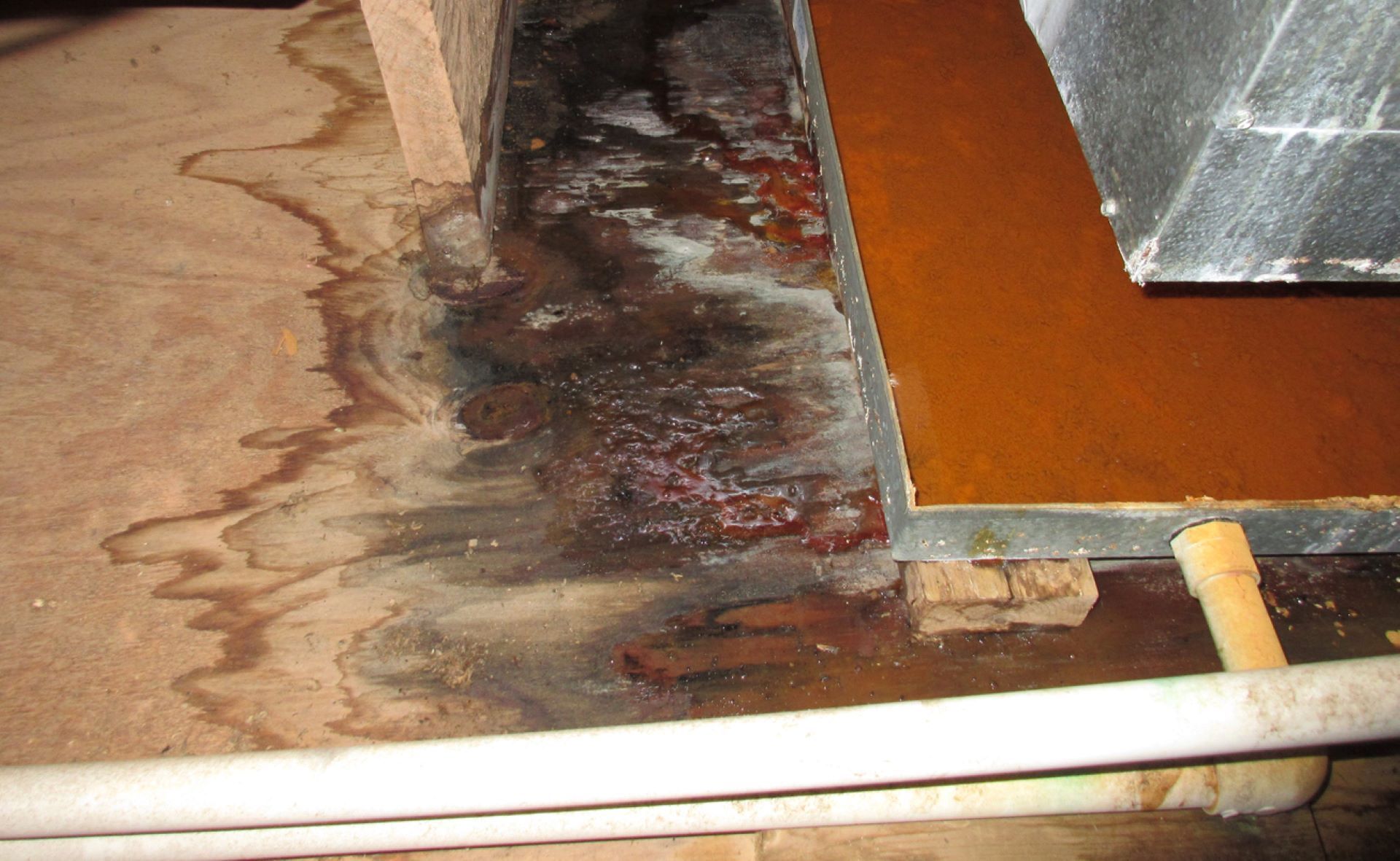 A piece of wood is sitting on top of a wooden floor next to a metal pipe.